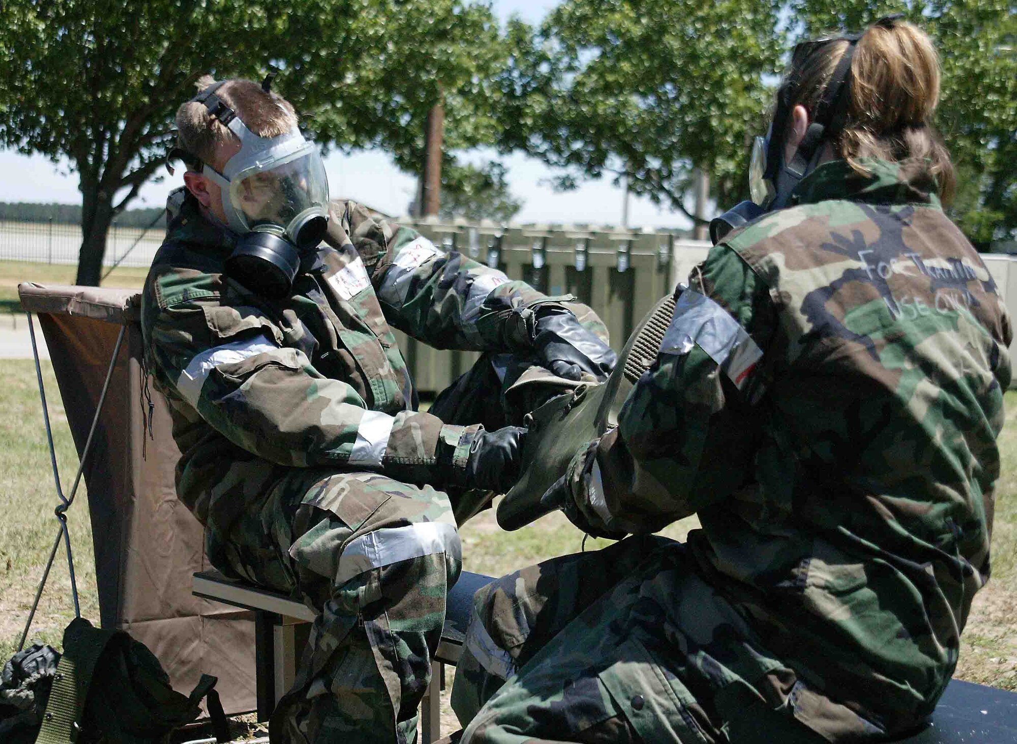 SHAW AIR FORCE BASE, S.C. -- Senior Airman Rachel Dunsmore (right), 20th Services Squadron food service specialist, removes the boots from Staff Sgt. Andrew Turnbull, 20th SVS food service accountant, at a decontamination processing line May 7 during the Phase II exercise. Phase II exercises evaluate Airmen's ability to operate and survive in deployed locations. (U.S. Air Force photo/Senior Airman John Gordinier)