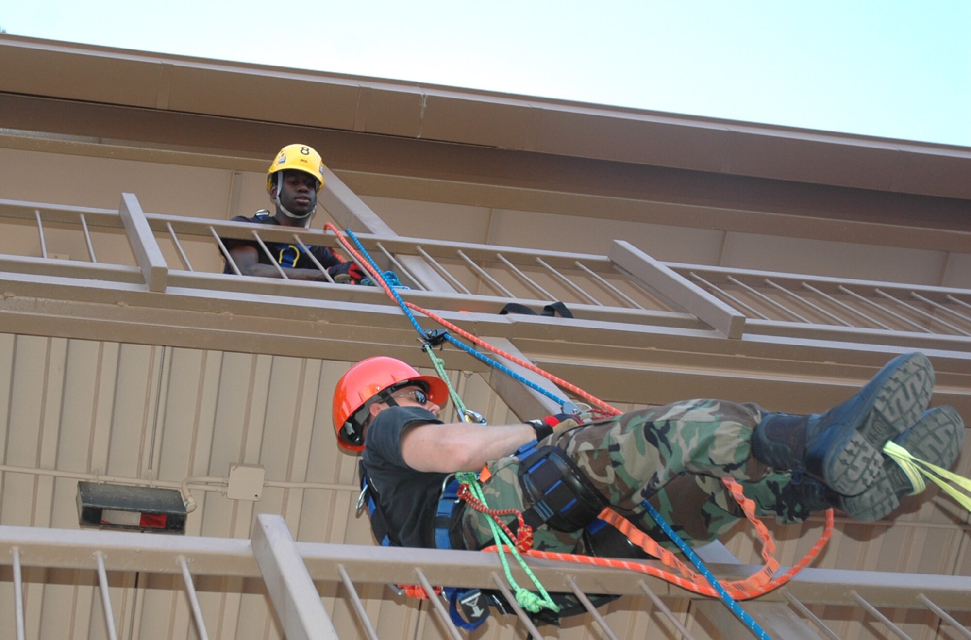 Staff Sgt. Daniel Rasmussen, a firefighter from D-M's fire protection flight, ascends a building using a life safety rope, while fellow firefighter Senior Airman Wilbert Carter guides from above. The rope rappelling was part of the high-angle operations portion of specialized rescue training taught at D-M April 16 through May 4 by three instructors from the United States Air Forces in Europe Fire Academy. (U.S. Air Force photo/Staff Sgt. Jake Richmond)