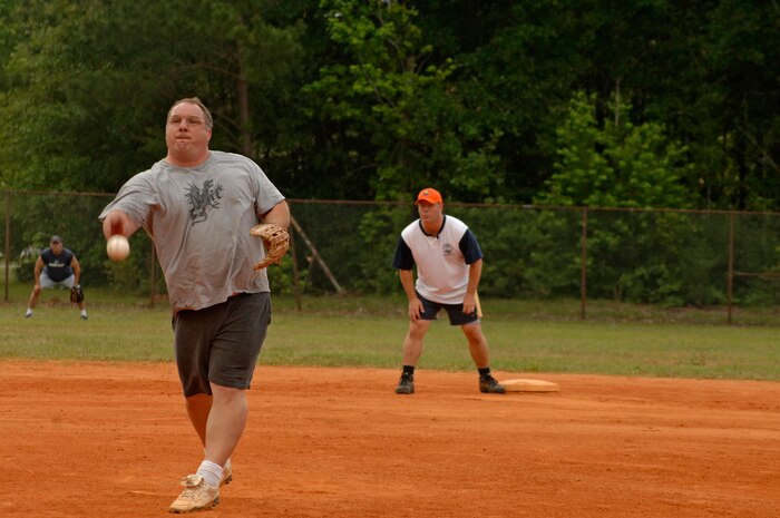 Pat Roche, Boeing Repair and Modification Services, pitches the ball to the next batter as Mark Rich, 1st Combat Camera Squadron, looks on and prepairs to run here Tuesday.  (U.S. Air Force photo/ Staff Sgt. April Quintanilla)