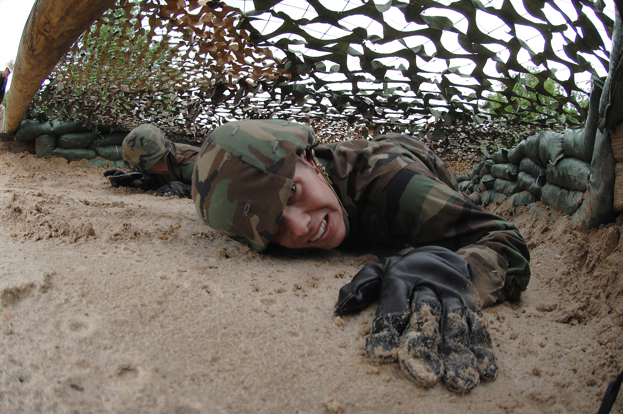A basic trainee low crawls through the first obstacle of the tactical assault course at the field training site on Lackland Air Force Base, Texas on May 2. This half-mile course, consisting of numerous obstacles, tests the trainees' newly-acquired defensive tactics skills and enforces the need to properly communicate with their wingmen. (U.S. Air Force photo/Tech. Sgt. Larry A. Simmons)