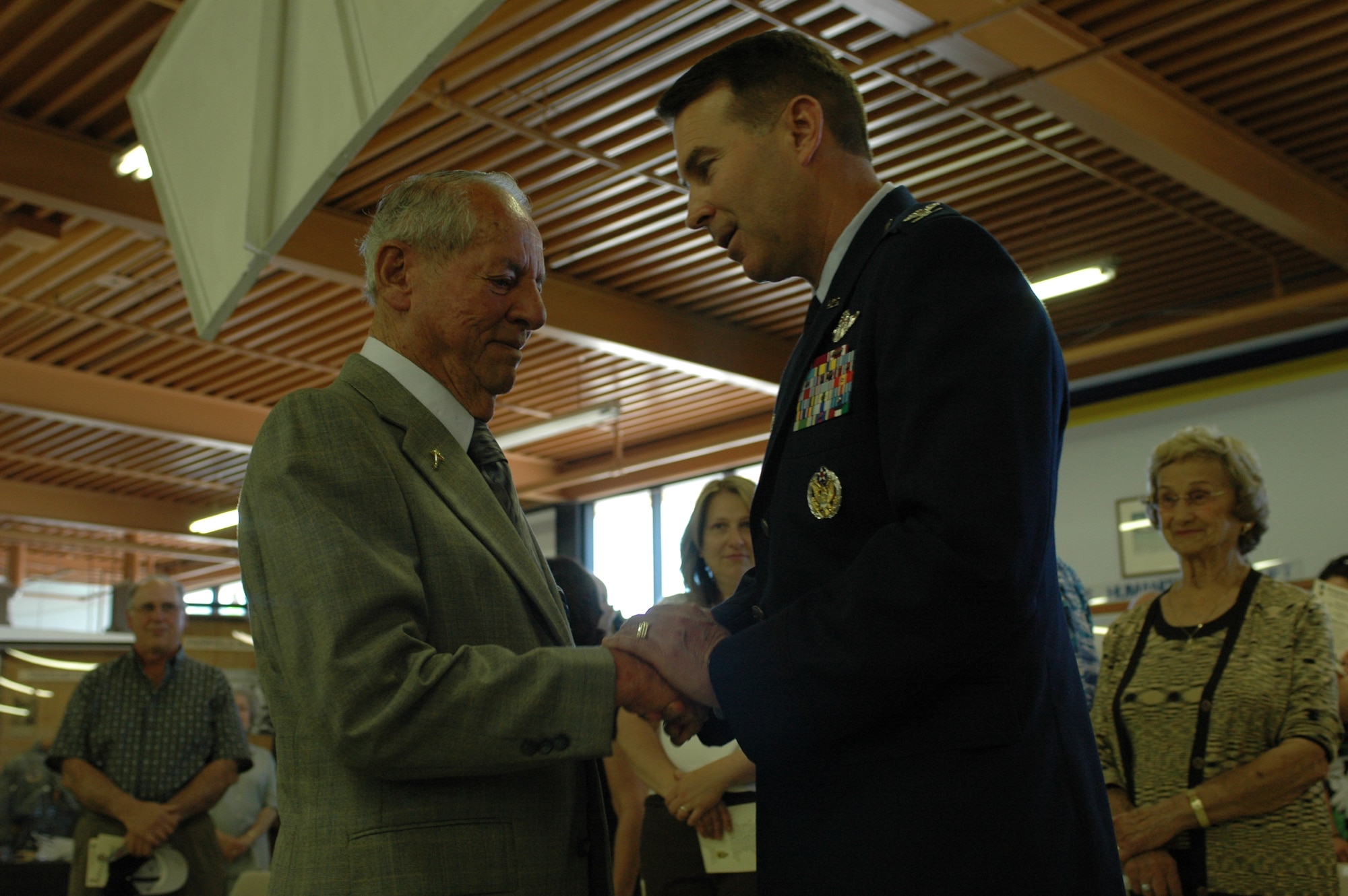 Mr. Art Cater (former Army Air Corps 1st Lt.) is congratulated by Col. Steve Arquiette, 60th Air Mobility Wing commander, after receiving the Distinguished Flying Cross during a ceremony at the Travis Air Museum May 7. Mr. Cater was presented the medal for his heroism as a pilot during World War II. (U.S. Air Force photo by Airman Kristen Rohrer)