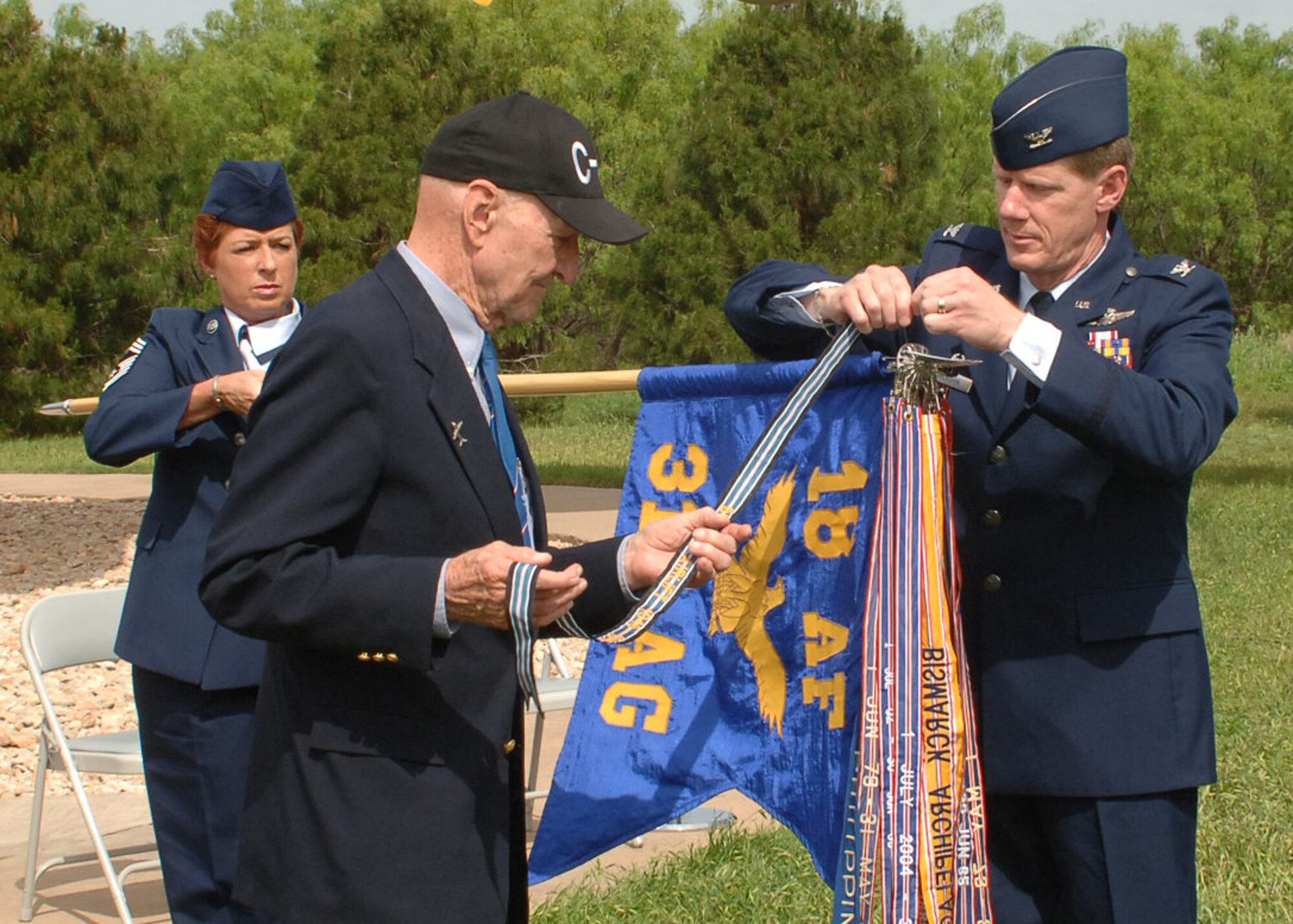 Retired Col. Gail Halvorsen, former C-47 and C-54 pilot with the 317th Troop Carrier Group, now known as the 317th Airlift Group, attaches The Berlin Airlift Streamer to the 317th AG guidon on behalf of SECAF during a ceremony here May 3. Colonel Kevin Jackson, 317th AG commander, and Chief Master Sgt. Debra Huntley, 317th AG acting command chief, assisted in the ceremony. The work the 317th AG did in 1948 and 1949 was similar to the work they do now in the Global War on Terror. (U.S. Air Force photo by: Airman 1st Class Felicia Juenke)