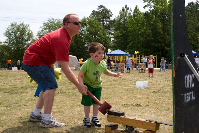 Jonathan Coffing, 5, gets a little help from his father, Staff Sgt. Cary Coffing, 437th Logistics Readiness Squadron, with the hammer strike game at the Month of the Military Child Festival on base, April 28. (U.S. Air Force photo/Airman Melissa Harper)