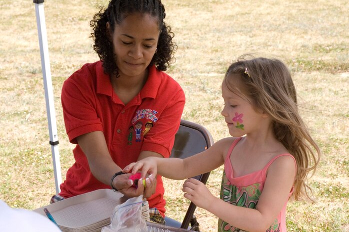 Alyssa Cutlip, 5, daughter of Tech. Sgts. Monti and Jennifer Cutlip, 437th Medical Group, works on a collage with the help of Soila Delgado-Hoover at the Month of the Military Child Festival on base April 28. (U.S. Air Force photo/Airman Melissa Harper)