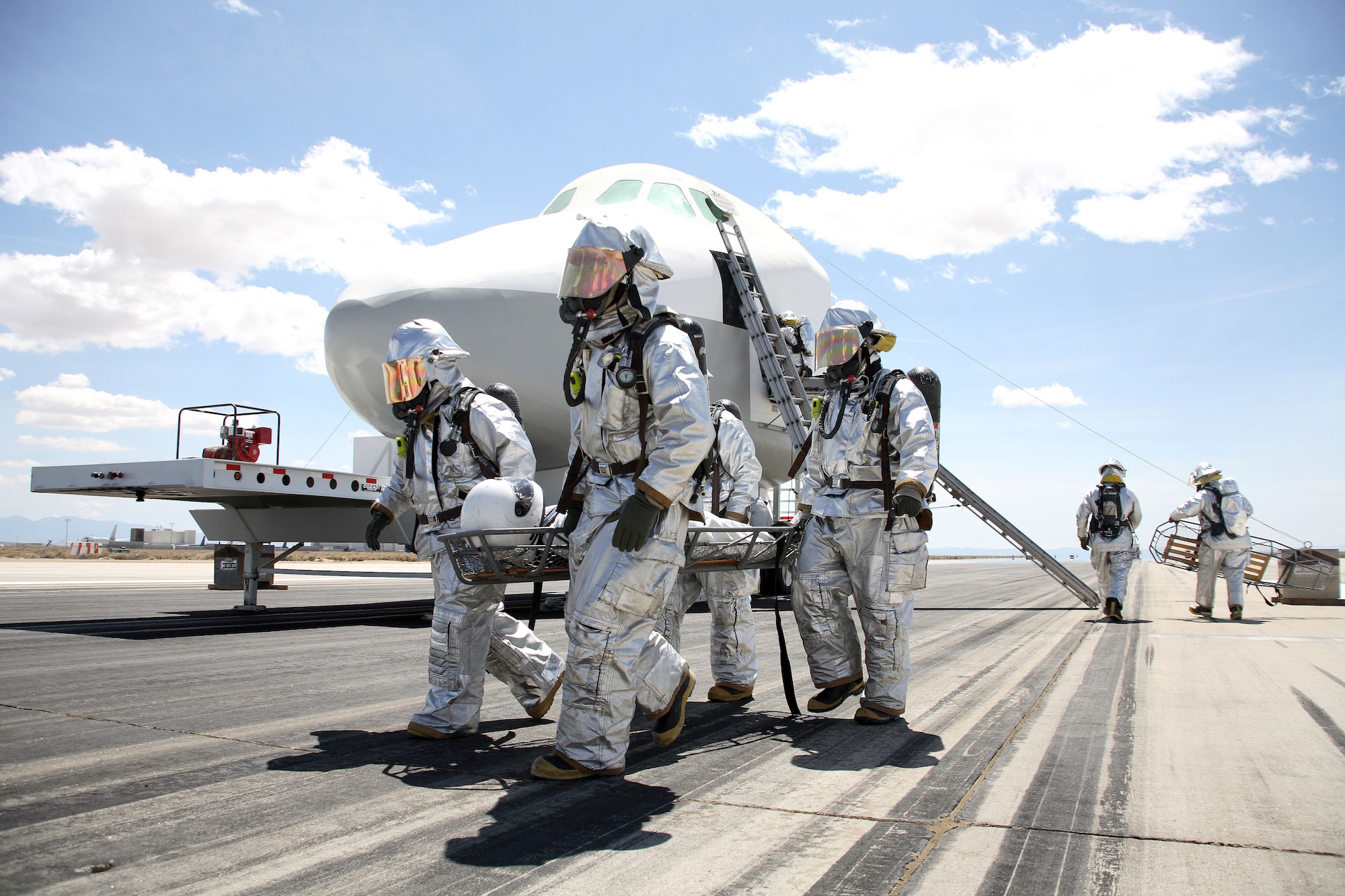 Edwards firefighters carry an "astronaut" during the space shuttle exercise here May 5. Various organizations on base participated to provide support and manpower. Space Shuttle Atlantis, which will perform the STS-117 mission to the International Space Station, is scheduled to lift off in June. (Photo by Jet Fabara)