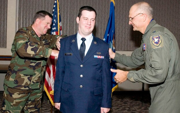 Col. Bryan Gallagher (left), 95th Air Base Wing commander, and Col. Arnie Bunch, 412th Test Wing commander, tack stripes on to Staff Sgt. Thomas Gilchrist during the Team Edwards Promotion ceremony at the Conference Center here April 30. (Photo by Chad Bellay)