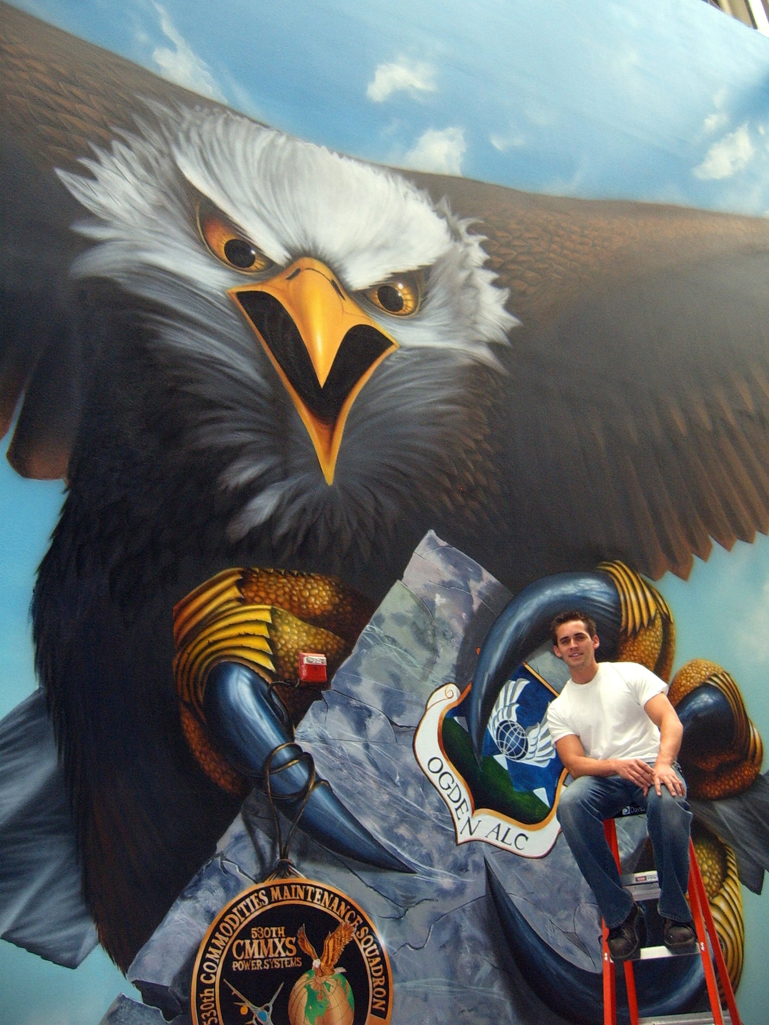 Jasey Colunga, machinist with the 530th Commodities Maintenance Squadron, leans on his most recently completed artwork at Hill Air Force Base. This is the single largest work of art Mr. Colunga has completed. The entire mural spans 170 feet by 35 feet, and is too wide to capture in a single photo. Drafts for the mural began with roadmaps from Texas to Utah representing the connection the unit has had with Texas in the past. Those drafts were tossed aside, however, and replaced with an all encompassing picture of Utah. The mural depicts southern Utah on the left and northern Utah on the right side. “The mural is really just to boost morale in our building,” said Mr. Colunga. “It turns our industrial workplace into an interesting shop that people remember.” Courtesy Photo