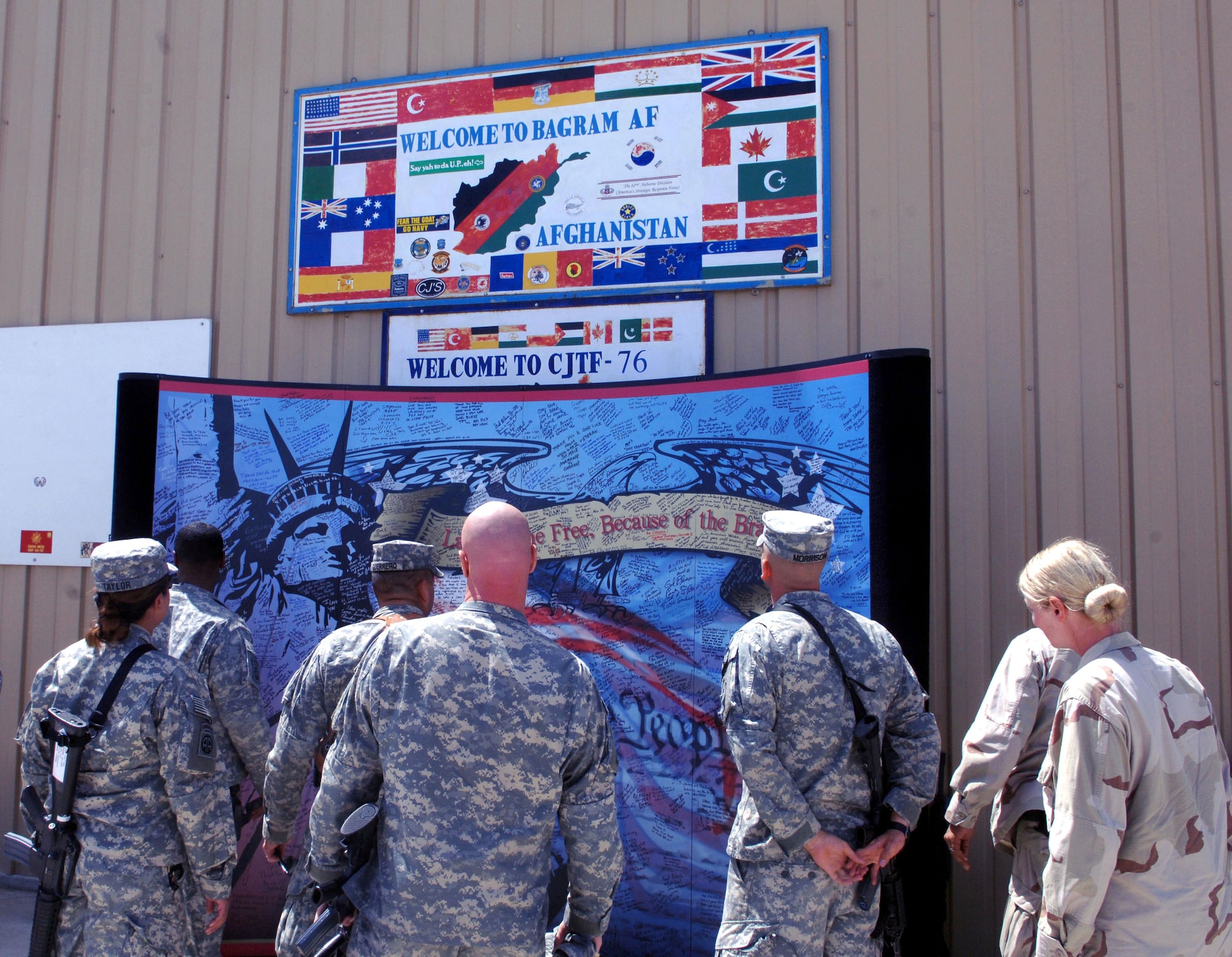 Servicemembers arriving at the passenger terminal May 9 at Bagram Airfield, Afghanistan, examine a mural donated by a pair of artists Paul and David Eisemann. The mural has messages and signatures from many first responders in the 9/11 attacks in New York, Pennsylvania and the Pentagon. (U.S. Air Force photo/Staff Sgt. Kevin Tomko)
