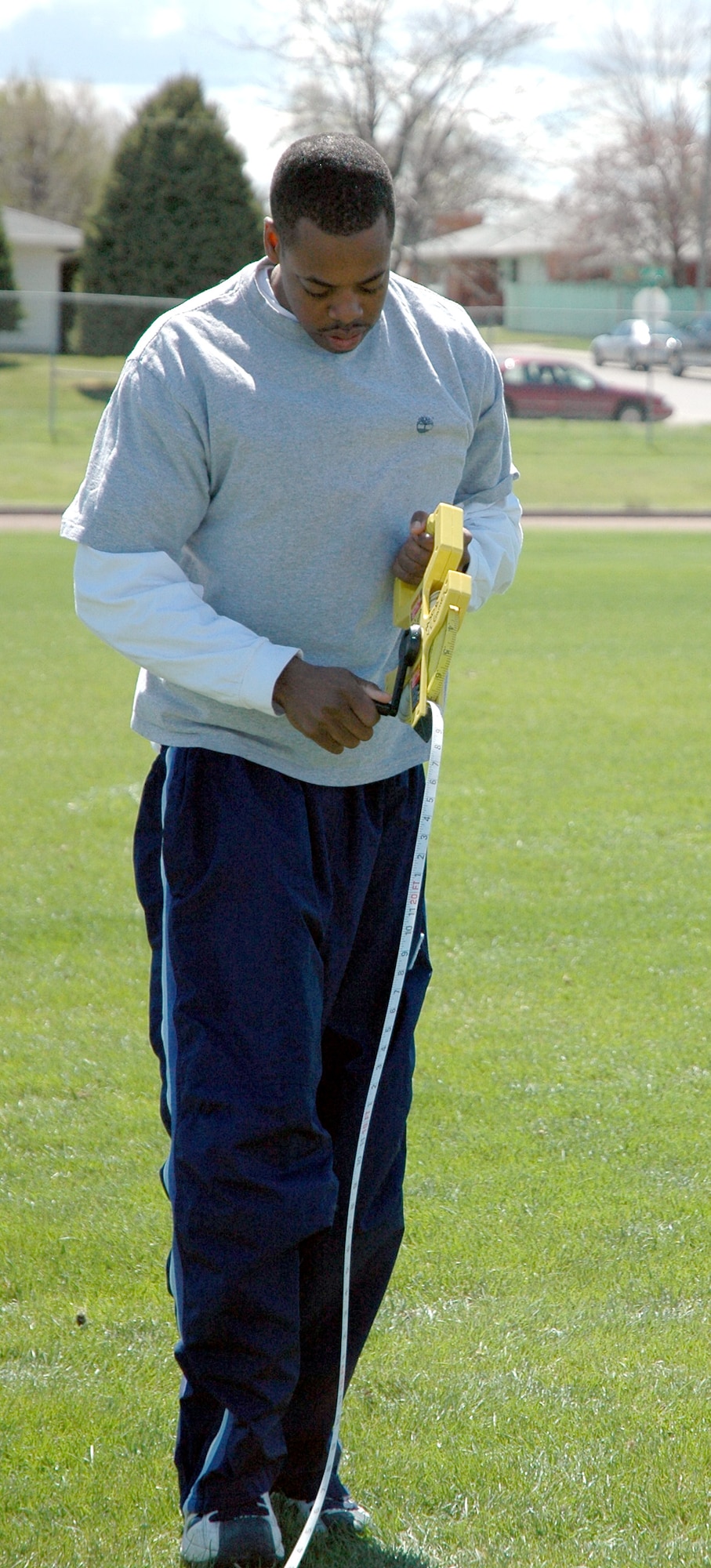 Senior Airman Jamaal Benton, 341st Missile Security Forces Squadron, rolls up the tape measure after measuring an athlete’s shot put toss. (U.S. Air Force photo / Valerie Mullett)