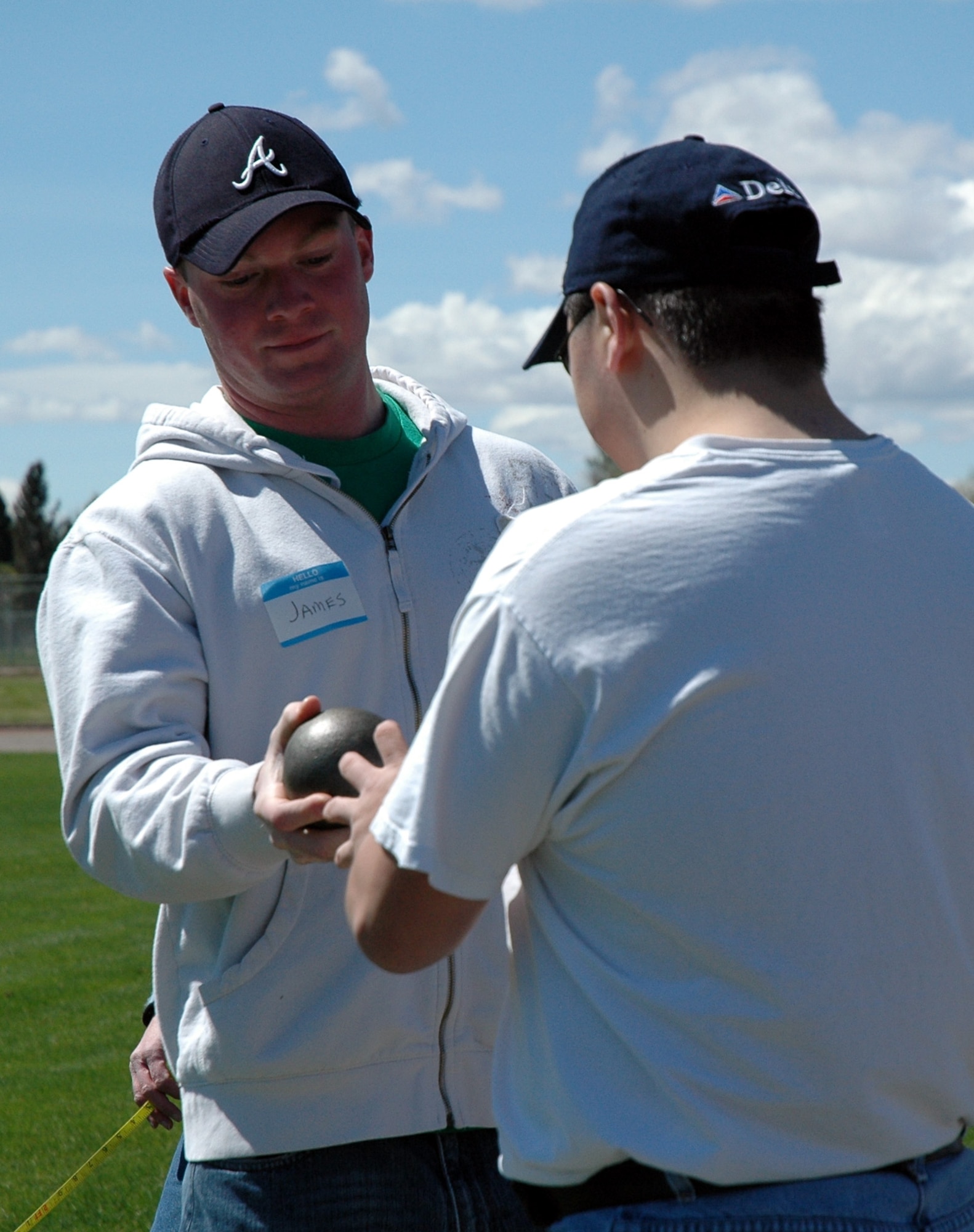 Airman James Watson, 341st MSFS,  hands a competitor the shot put after retrieving his first toss. (U.S. Air Force photo / Valerie Mullett)