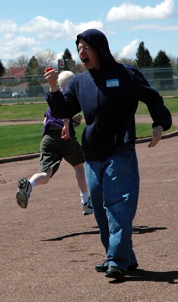 Airman 1st Class Kyle Sawyer, 741st missile security forces squadron, cheers Caleb, an athlete while timing his 60-yard dash finish. About 70 security forces members assisted at the Games for the Visually Impaired May 5-6 sponsored by the Montana School for the Deaf and Blind. (U.S. Air Force photo by Valerie Mullett)