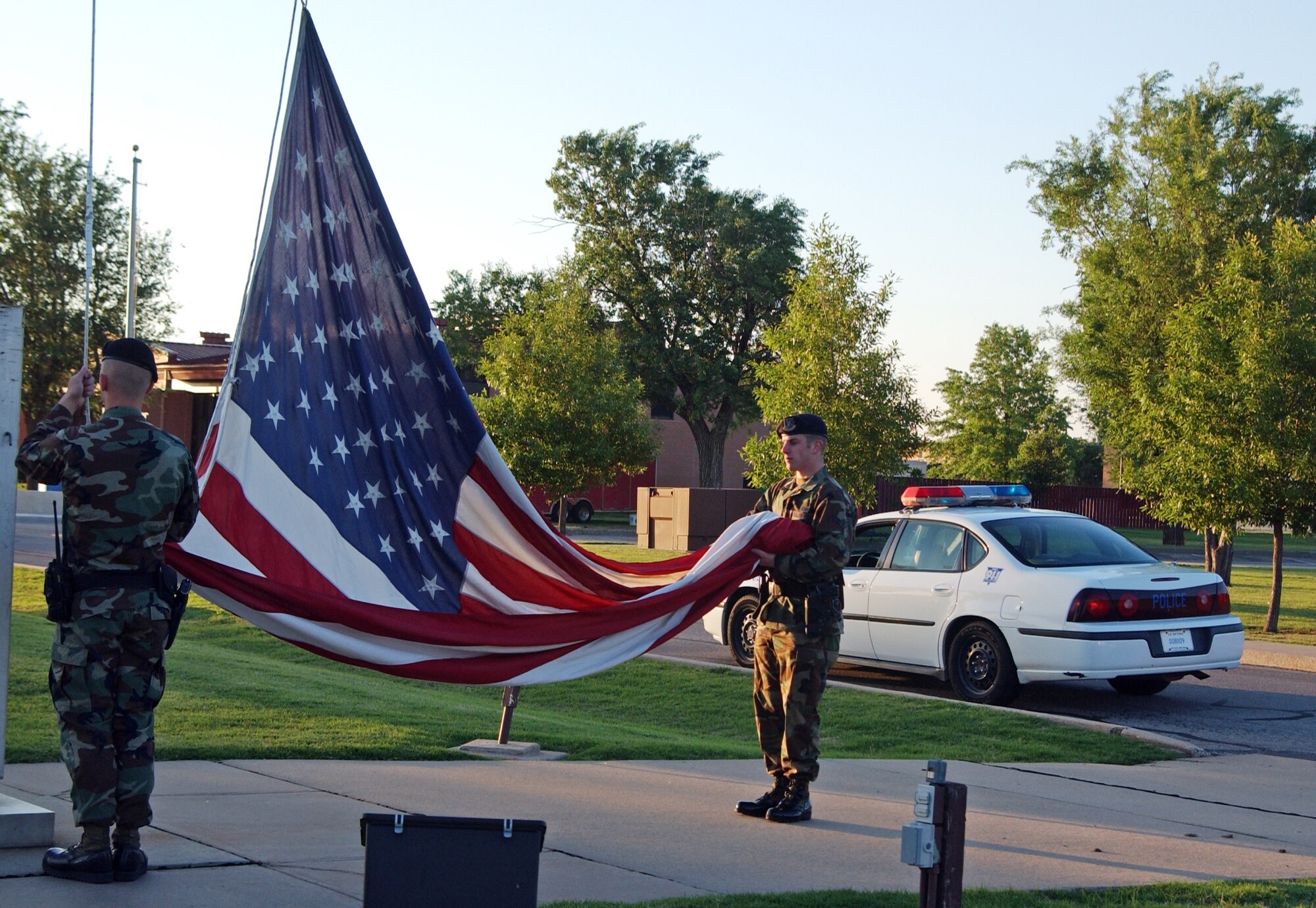 Airman (now Airman 1st Class) Ronald Ernest and Airman 1st Class (now Senior Airman)Peter Tripi, 71st Security Forces Squadron members, post the flag at half staff during May 15 reveille last year in honor of National Peace Officers Memorial Day observance.This year's National Police Week begins Monday. (U.S. Air Force by Frank McIntyre)