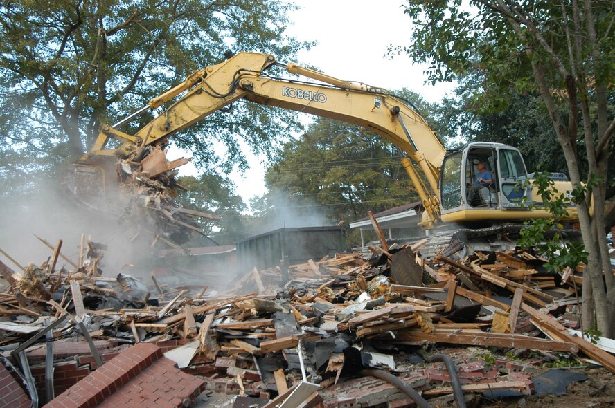 A Carpenter Construction employee uses a trackhoe to demolish a house on Tenth Street earlier this year. Similar housing demolitions will take place beginning in June, as a contract has been awarded allowing for the demolition of 212 homes in the Pine Oak and Crestview subdivisions. U. S. Air Force photo by Sue Sapp