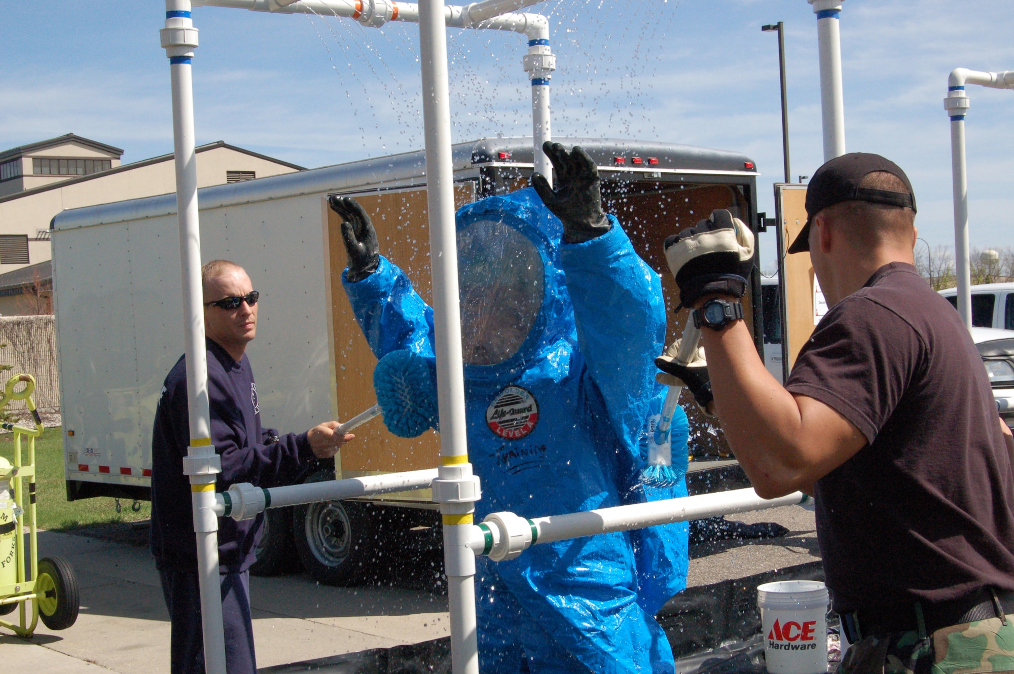 Tech. Sgt. Scott Smoot (far left) and Tech. Sgt. Michael Cain (right), 319th Civil Engineer Squadron Fire Department, scrub hazardous material off Airman Nicholas Gallagher in the decontamination line during a hazmat technician certification course here May 7. (U.S. Air Force photo/Airman 1st Class Ashley Coomes)