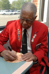 Tuskegee Airman and retired Chief Master Sgt. Grant Williams Sr. autographs a paper printout of the Congressional Gold Medal during a ribbon cutting ceremony at the Langley Main Exchange April 25. The ceremony marked the opening of a permanent display of Tuskegee Airmen memorabilia in the exchange, next to the food court.  President Bush and Congress awarded the Congressional Gold Medal to the Tuskegee Airmen March 29 in Washington D.C., for their efforts in World War II.  (U.S. Air Force photo/Staff Sgt. Katrina Shellman)