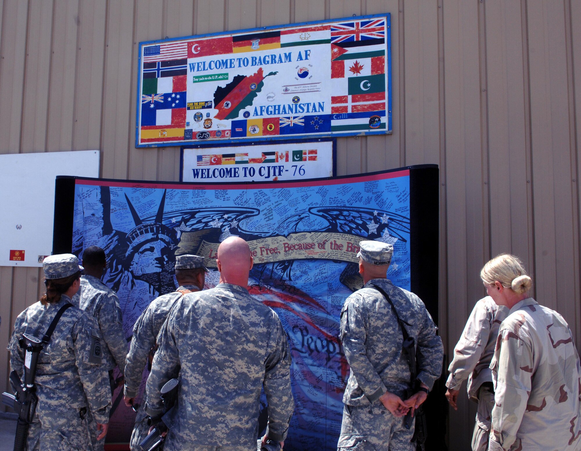 Service members arriving at the Bagram Airfield passenger terminal examine a mural donated by a pair of artists Paul and David Eisemann. The mural has messages and signatures from many first responders in the 9/11 attacks in New York, Pennsylvania, and the Pentagon. (U.S. Air Force photo/Staff Sgt. Kevin Tomko)
