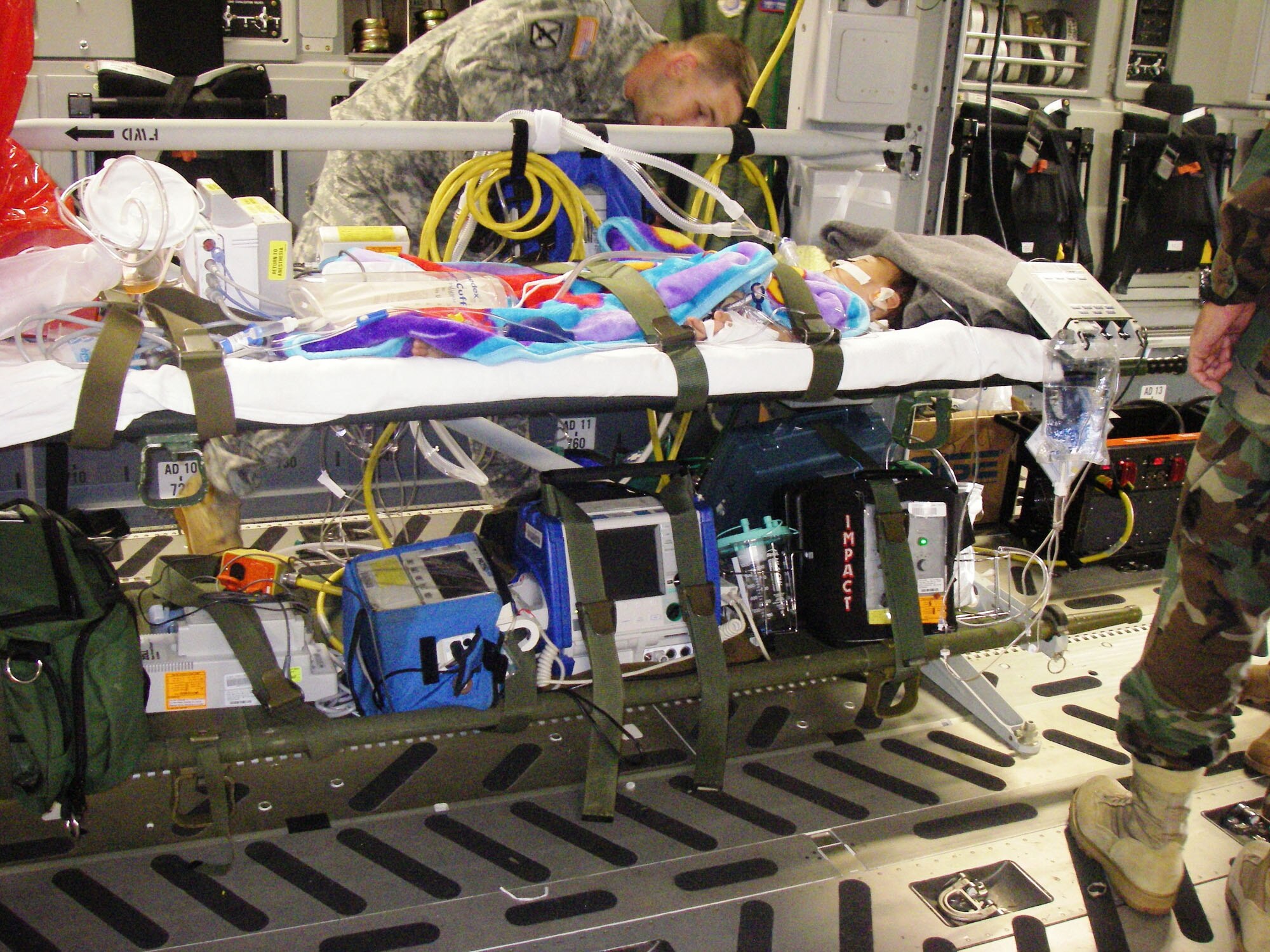 An aeromedical evacuation team member tends to two-year-old John Tenorio who is on a patient litter and hooked up to mobile critical care equipment while enroute to Hawaii on a U.S. Air Force C-17 from Hickam AFB. (U.S. Air Force Photo by Lt. Col. Jimmy Barrow) 