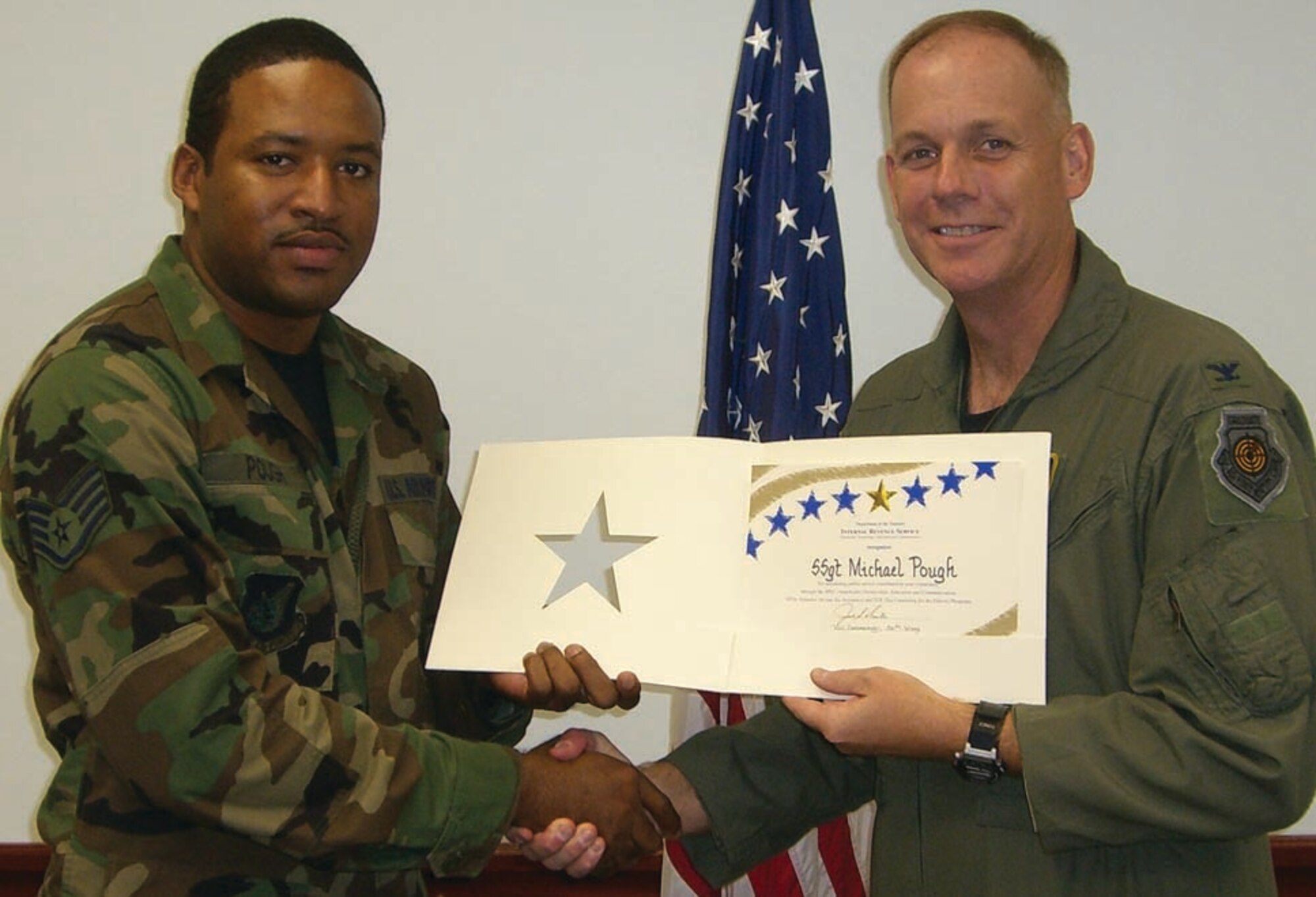 Col. Joel Westa congratulates Staff Sgt. Michael Pough for his contributions to the tax center.  Sergeant Pough was the top tax preparation volunteer for the year.  