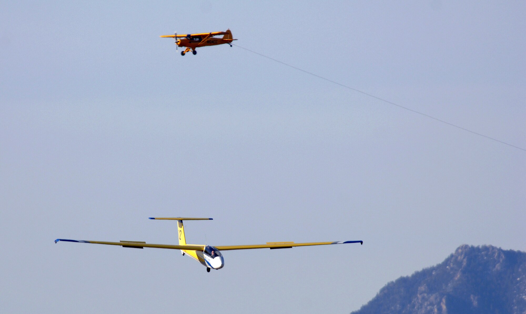 A TG-10B glider comes in to land as a Piper Super Cub tow plane circles the airfield at the U.S Air Force Academy, Colo. Soaring occurs at the Academy on a year-round basis. The glider mission is to form the foundation of cadet exposure to military aviation, build character and help motivate cadets toward a career in the United States Air Force. (U.S. Air Force photo/David Armer)
