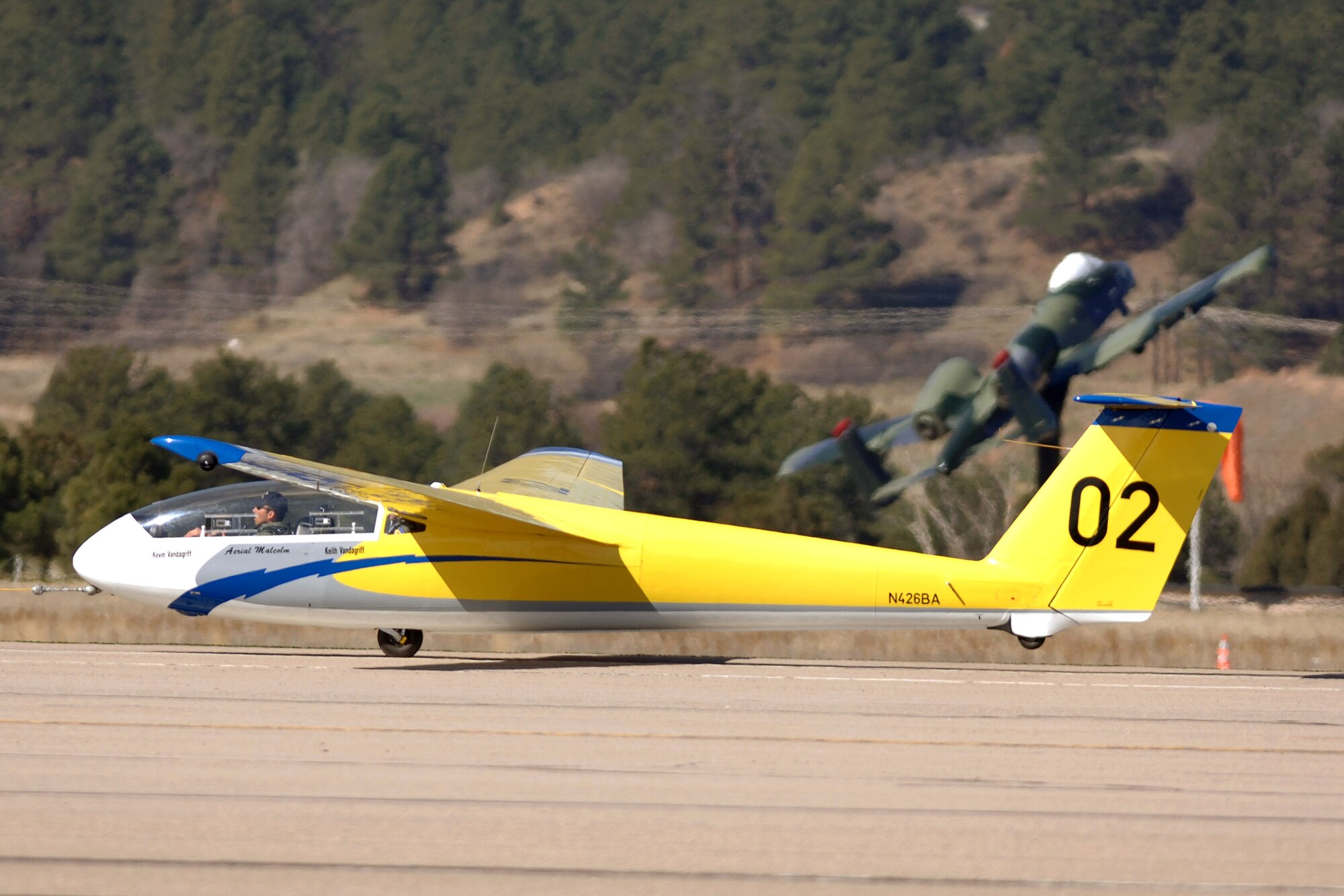 A TG-10B glider lifts into the air as it is towed down the runway by a Piper Super Cub tow plane at the U.S. Air Force Academy, Colo. The 94th Flying Training Squadron conducts more than 15,000 training and competition glider sorties annually, focused on developing leadership in more than 4,000 Air Force Academy and ROTC cadets. (U.S. Air Force photo/David Armer)