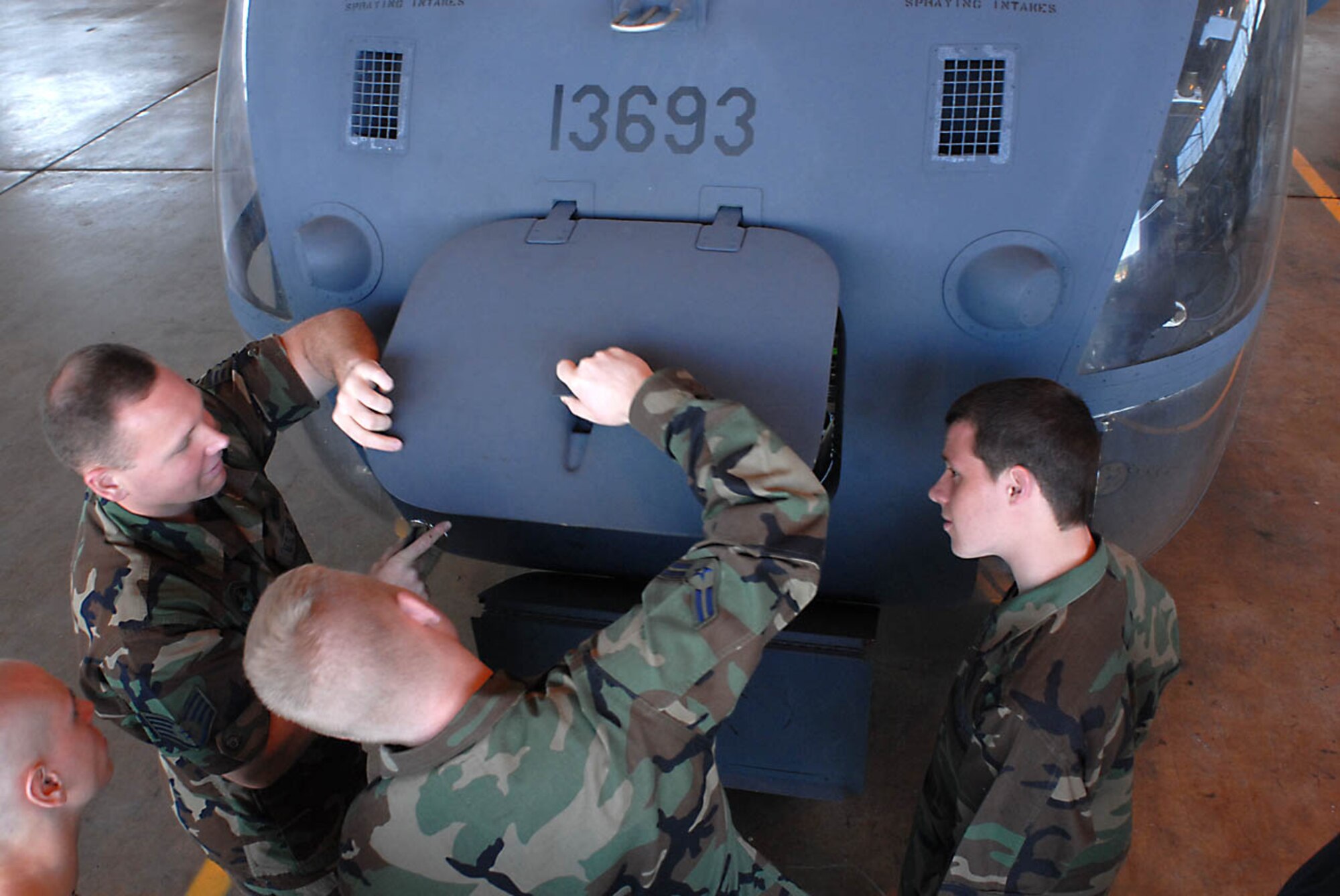 Staff Sgt. Michael Black, MH-53M Pave Low IV Mission Ready Airman Course instructor with the 360th Training Squadron detachment 1, Airman 1st Class Adam Guthrey and Airman John Hoffman open a cowling to perform an inspection on the nose electronic bay. (U.S. Army photo/J. Raynel Bishop Koch)