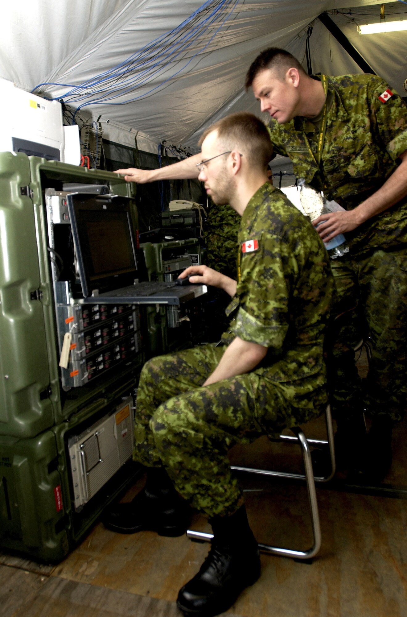 Canadian army Master Cpl. Terry Perron double checks the satellite connection of tactical satellite communications while Pfc. Frederick Leproham observes.  They are in Lager Aulenbach, Baumholder, Germany, participating in Combined Endeavor 2007, a U.S. European Command-sponsored exercise that brings the U.S. and other nations together, especially those in NATO or Partnership for Peace, to plan and execute interoperability testing of command, control, communications and computer systems in preparation for future combined humanitarian, peacekeeping and disaster relief operations.  (U.S. Air Force photo/Staff Sgt. Nic Raven) 