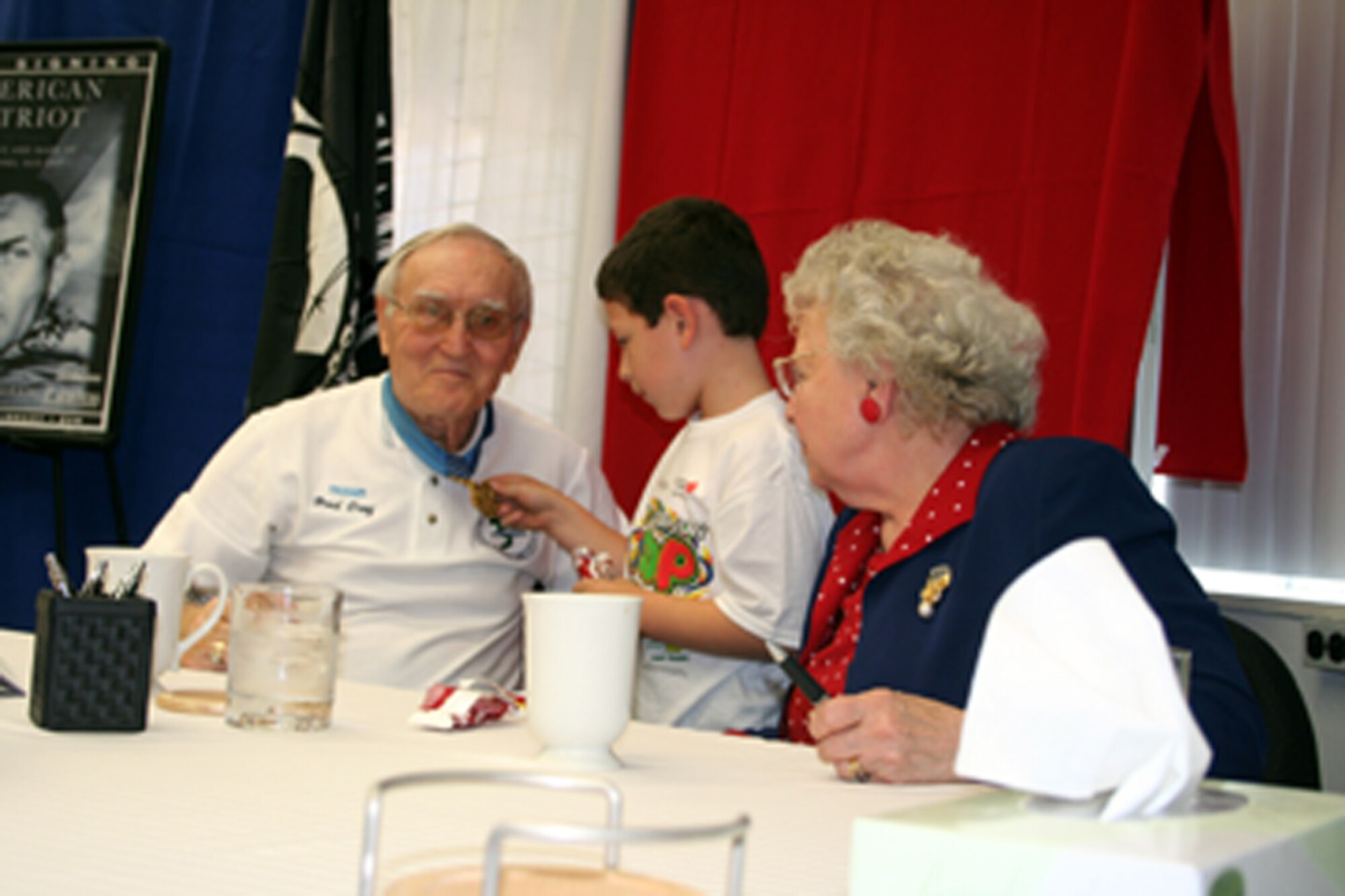 Retired Col. bud Day allows the child of a Team Hurlburt Airman to see his Medal of Honor up close while Col. Day's wife, Rose, explains what the medal stands for. Col. Day spoke at the U.S. Air Force Special Operations School May 7 before heading to the base library for a book signing, hand shaking session with Team Hurlburt Airmen and families. Col. Day is the most decorated living veteran, having served in the U.S. Army, the Marine Corps Reserves and ending with a 20 year Air Force career. (U.S. Air Force photo by Jamie Haig)