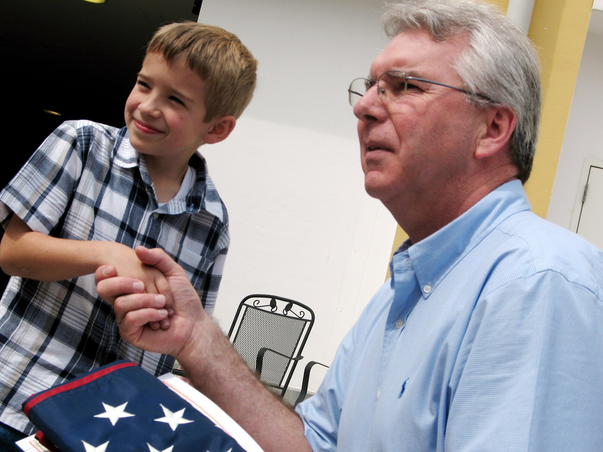 Brian Peterson presents an American flag to Aviano Elementary School principal Tim Erikson May 10 during the last meeting of the school year for the Aviano Elementary School Deployment Club. The flag had been flown at Brian's father's deployment location in Iraq. (U.S. Air Force photo/Airman 1st Class Justin Goodrich)