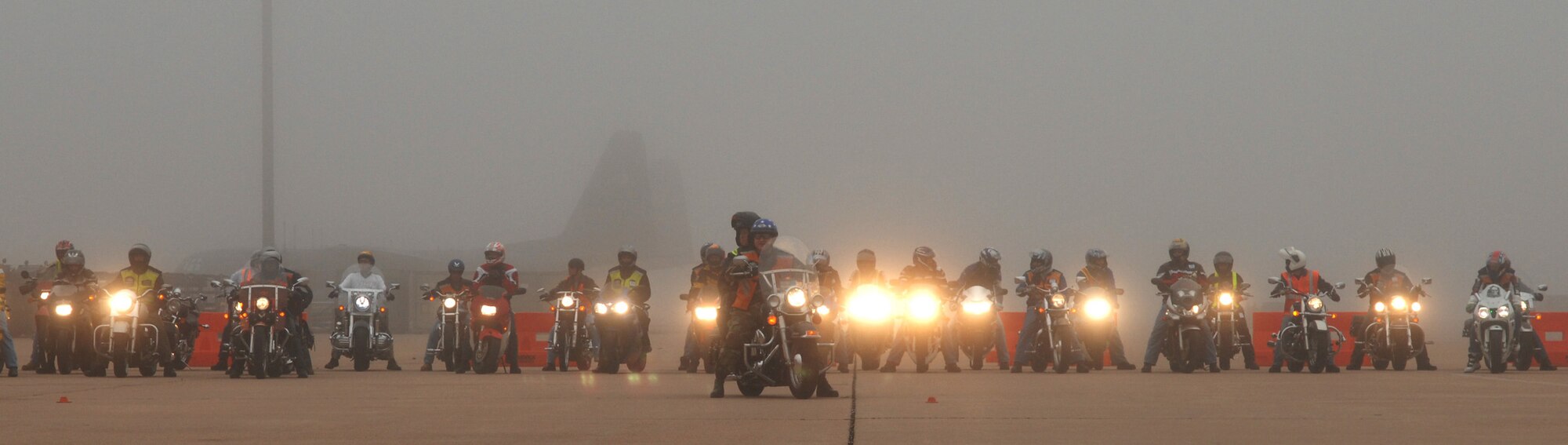 A C-130 silhouette peeks through the fog as 7th Bomb Wing Command Chief Master Sgt. Paul Wheeler and 317th Airlift Group Command Chief Master Sgt. Debra Huntley lead a pack of bikers on a parade around the base during the Team Dyess Motorcycle Rodeo May 11. This is part of a motorcycle safety and training program held annually to promote esprit de corps. (U.S Airforce photo by Staff Sgt. Araceli Alarcon)
