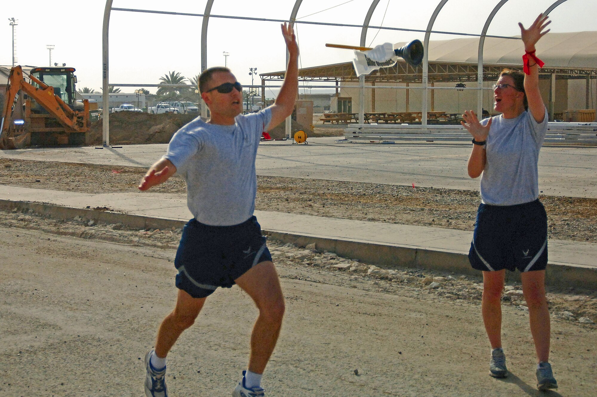 James Scott and Kathryn L. Bass, 447th Expeditionary Security Forces Squadron, complete a recent 5K relay by passing the "baton," a toilet plunger. Scott is training for the 2007 U.S. Air Force Marathon at Baghdad International Airport, Iraq. (U.S. Air Force)