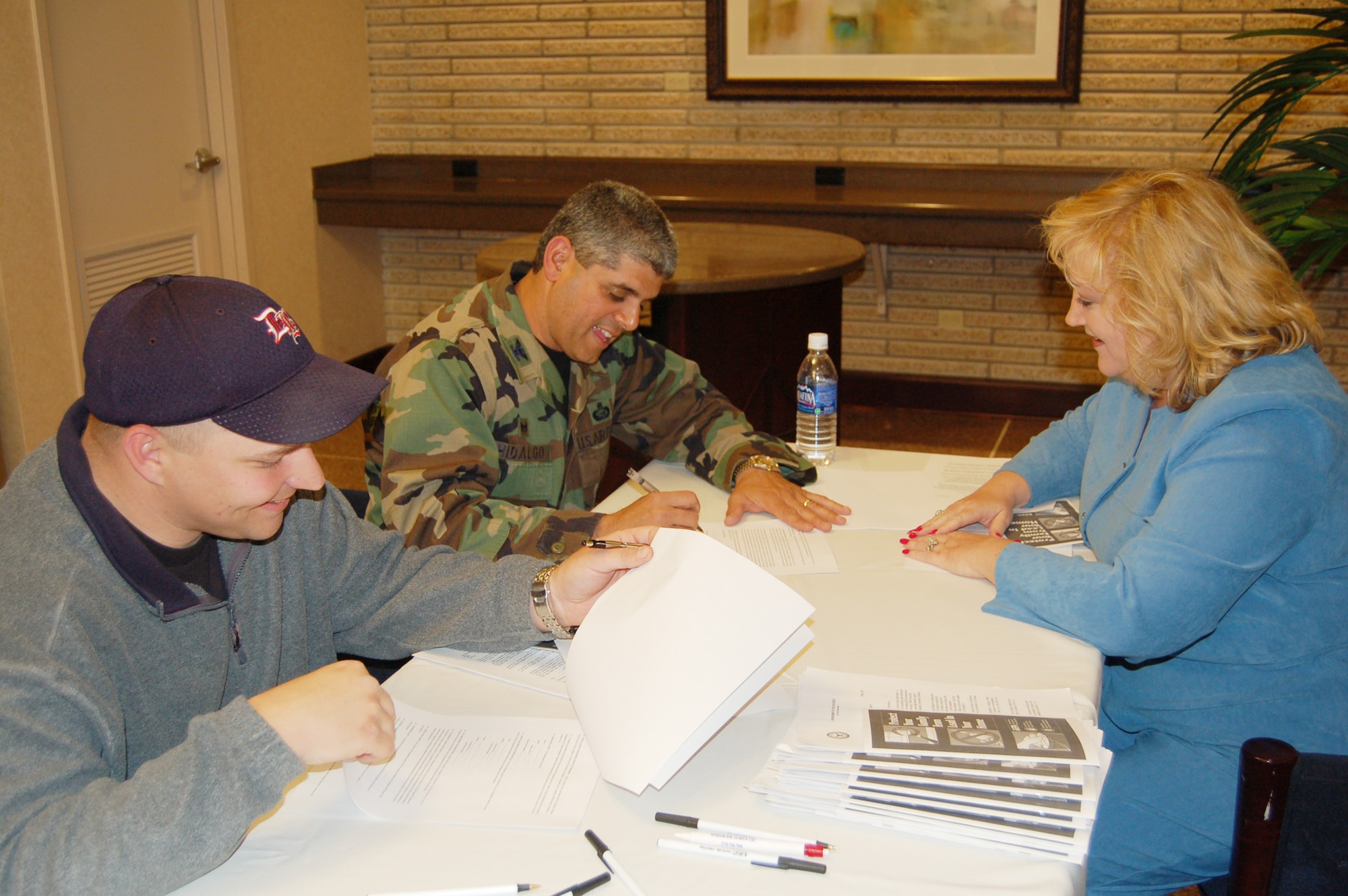 Tech. Sgt. Harry Metheny (left), and Col. Manny Hidalgo sign new leases with Paula Potter-Hayes, property manager with Actus Lend Lease and Tierra Vista Communities. Attending a town hall meeting May 9, the Airmen were among the first to sign lease agreements with Tierra Vista, which will begin managing housing on Peterson this summer. (U.S. Air Force photo by Corey Dahl)