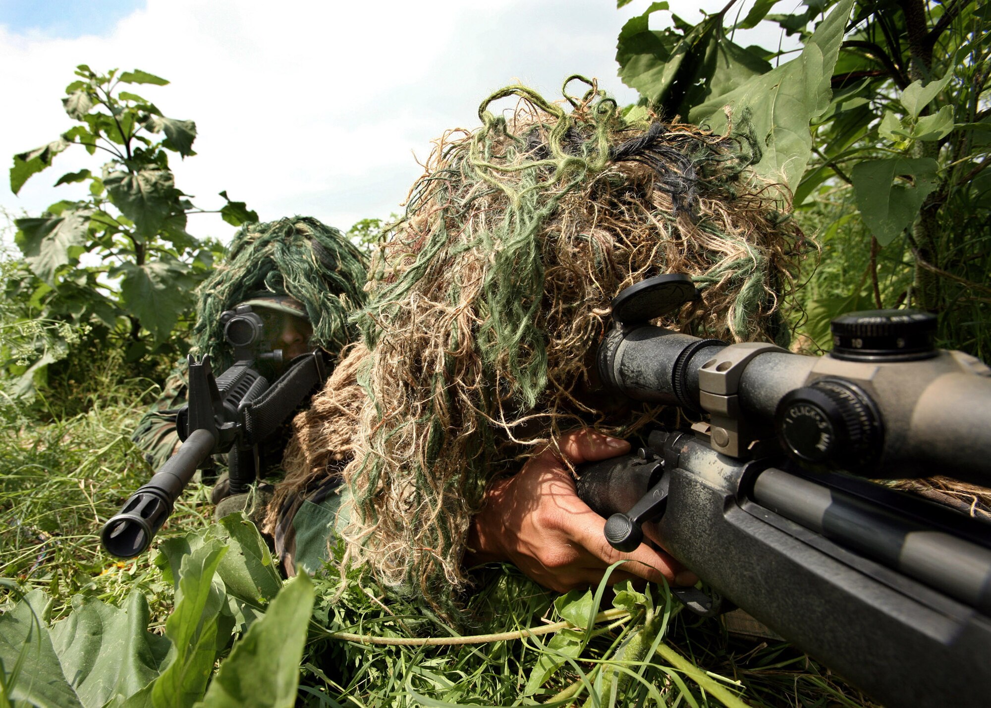 Senior Airman Andrew Caro (left) and Staff Sgt. Dustin Maglinti take aim at a target building during a training exercise May 4 at Lackland Air Force Base, Texas. They are close-precision-engagement-team members and blend in to their surroundings, thanks to their "ghille suits." (U.S. Air Force photo/Robbin Cresswell)