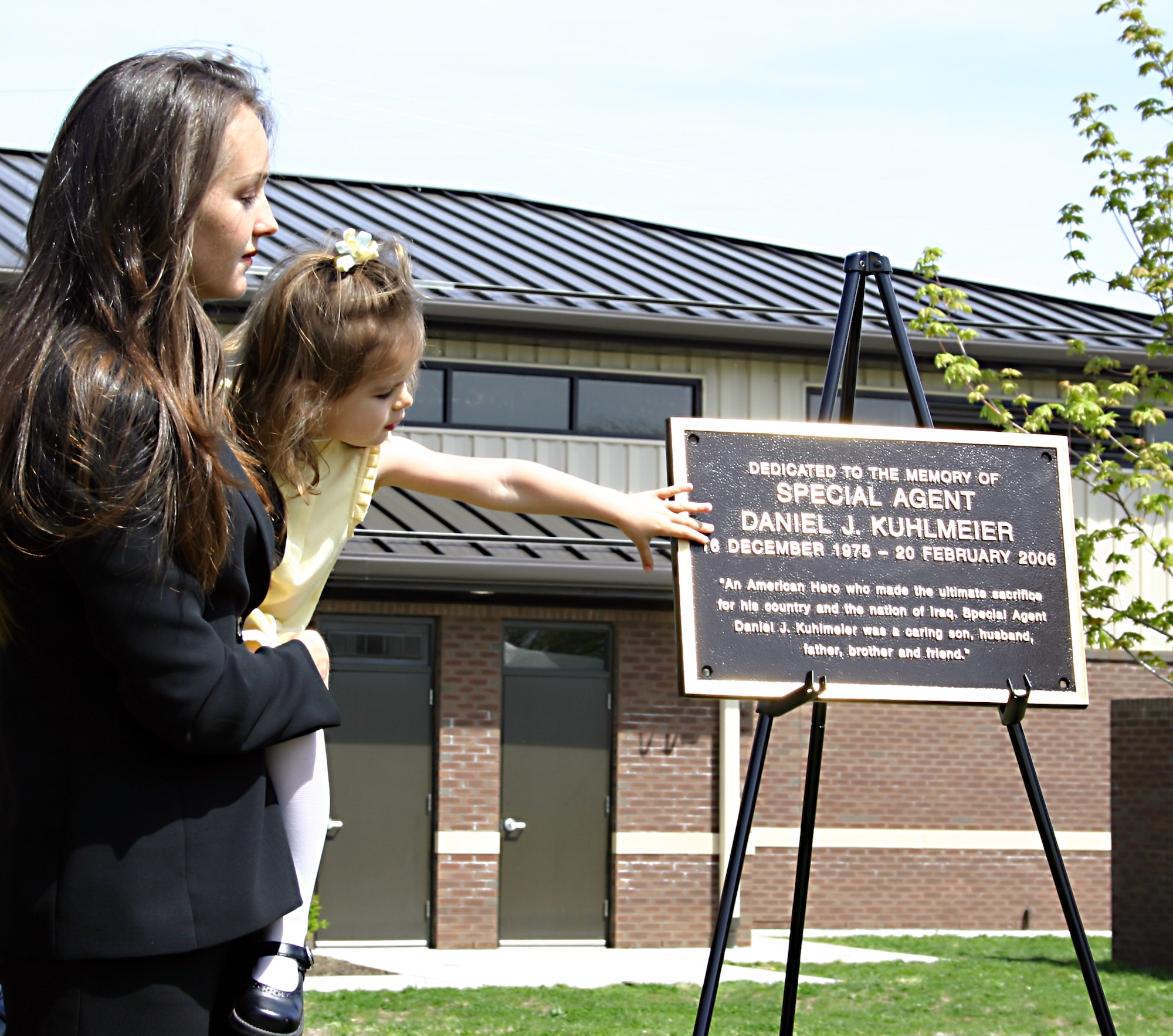 Tanya Kuhlmeier and daughter Kaya examine the plaque honoring Air Force Special Agent Daniel Kuhlmeier that was unveiled at a May 4 ceremony naming the Commercial Vehicle Gate at Fort Dix for him and Army Staff Sgt. James McNaughton. Both servicemen were killed in Iraq. 