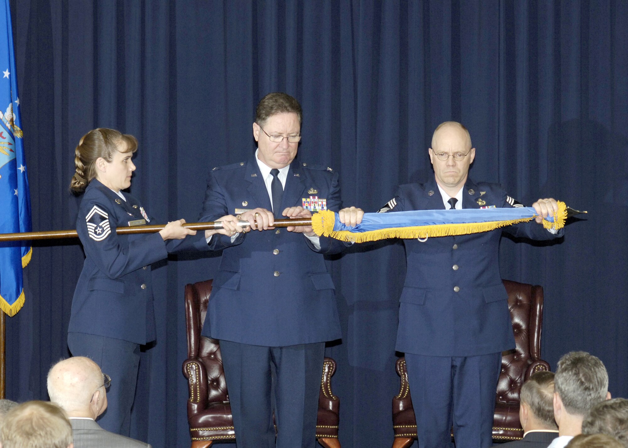 Senior Master Sgt. Cynthia Johnson, NCO Academy director of education, holds the flag as Col. Albert J. Bowley, College for Enlisted Military Education commander, and Chief Master Sgt. Lee Wofford, NCO Academy 13th and final commandant, encased the flag during the inactivation ceremony held May 3 here. 