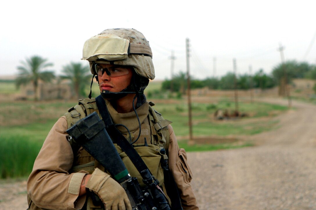 Cpl. Brent Jackson, a squad leader with 4th Platoon, Charlie Company, Task Force 1st Battalion, 4th Marines looks down the road at his fellow Marines while patrolling the town.  4th Platoon used two observation posts during the night to keep the town safe from insurgency.