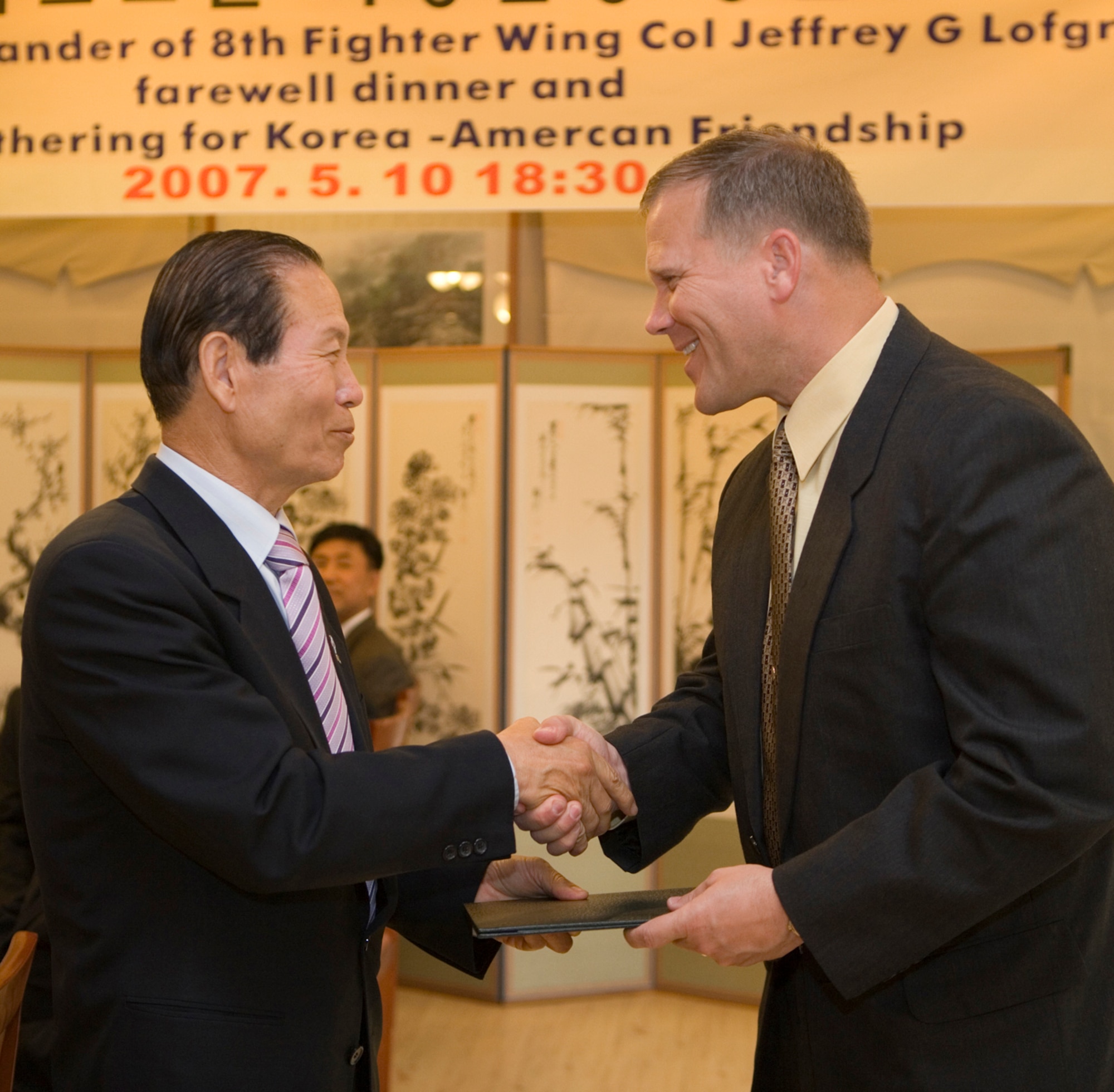 GUNSAN CITY, Republic of Korea  May 10, 2007 -- Col. Jeff "Wolf" Lofgren, 8th Fighter Wing commander (right) and Gunsan City mayor Moon, Dong Shin shake hands during a farewell dinner May 10. Colonel Lofgren was also named an honorary citizen of Gunsan City for his "contribution to the development of Gunsan," according to the awards plaque. The 8th FW commander was joined by the unit's group commanders, where they were each recognized for their service to the community. (Courtesy photo)