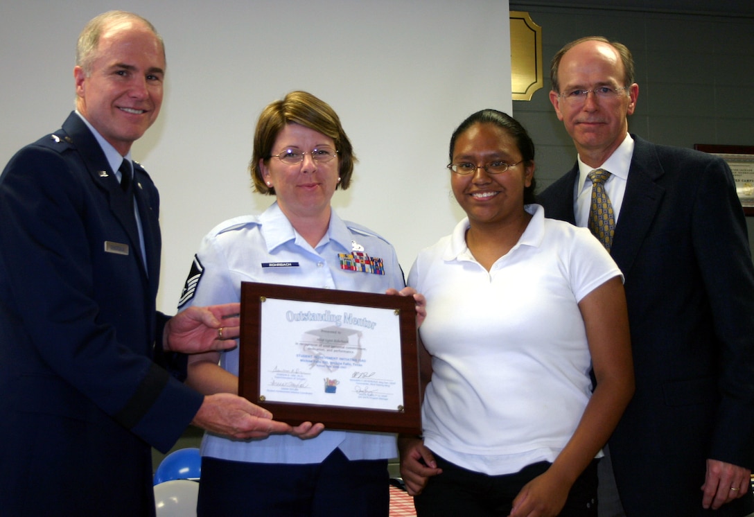 82nd Training Wing Commander Brig. Gen. Richard Devereaux and Wichita Falls Independent School District superintendent Dr. Dawson Orr present an Outstanding Mentor plaque to Master Sgt. Lynn Rohrbach, 365th Training Squadron, in a ceremony at Washington-Jackson Elementary School May 10. Sergeant Rohrbach serves in the Student Achievement Initiative as a mentor to Zundy Junior High School student Aidee Rubio, also pictured. (U.S. Air Force photo/Staff Sgt. Tonnette Thompson)
