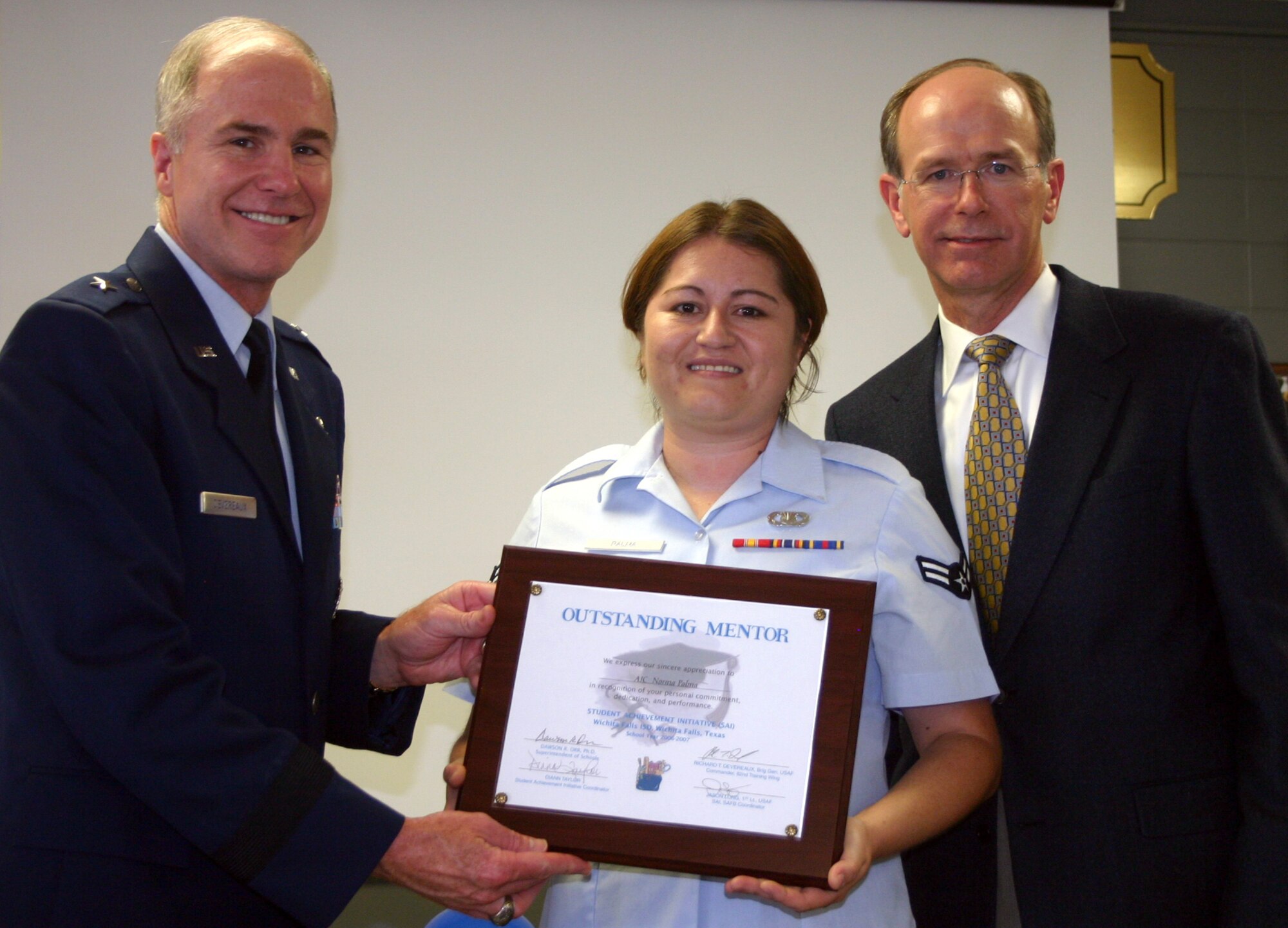 82nd Training Wing Commander Brig. Gen. Richard Devereaux and Wichita Falls Independent School District superintendent Dr. Dawson Orr present an Outstanding Mentor plaque to Airman 1st Class Norma Palma, 82nd TRW, in a ceremony at Washington-Jackson Elementary School May 10. (U.S. Air Force photo/Staff Sgt. Tonnette Thompson)