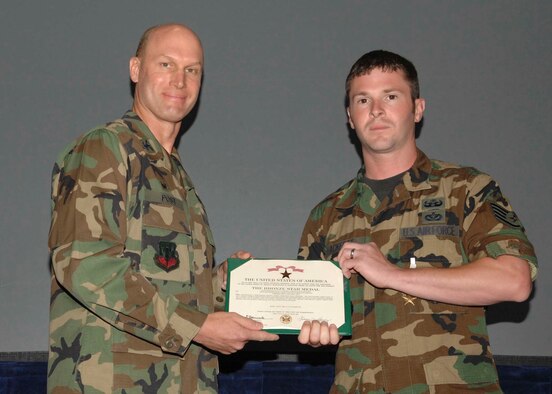 SHAW AIR FORCE BASE, S.C.-- Col. James Post, 20th Fighter Wing commander, presents Staff Sgt. Scott Ackeret, 20th Civil Engineer Squadron explosive ordinance disposal technician, a Bronze Star May 11 in hangar 1200 during a commander's call. The bronze star is awarded to servicemembers who distinguished themself by heroic or meritorious achievement or service. Sergeant Ackeret received the medal for his excellence as an EOD team leader, while deployed to Iraq. He ensured the safety of more than 16,000 coalition forces, multinational contractors and local nationals. He also executed more than 105 combat missions under the threat of insurgent attacks to exploit, render-safe, recover and destroy improvised explosive devices and unexploded ordnance. His team conducted over 25 counter-insurgent IED search and destroy combat missions along critical supply routes. (U.S. Air Force photo/ Airman 1st Class William Coleman)