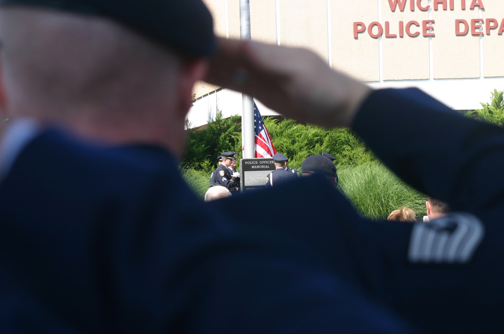 Members of the Wichita Falls Police Department Honor Guard raise the American flag May 14 as an 82nd Security Forces Squadron member gives the proper respect. Sheppard, WFPD and officers from other area law enforcement agencies honored officers killed in the line of duty during a ceremony. (U.S. Air Force photo/John Ingle)