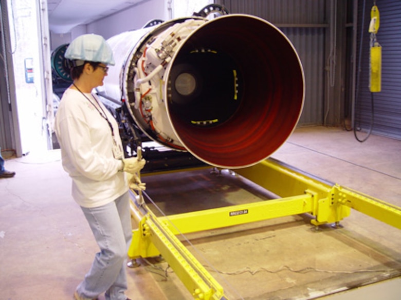 AEDC employee Cindy Yates with a Minuteman ICBM upper stage rocket motor Jan. 10.  As a safety precaution, she is using a hand brake to prevent the motor from rolling out of control on AEDC’s new rocket rail transport system that improves the process for moving motors into position to be prepared for testing.