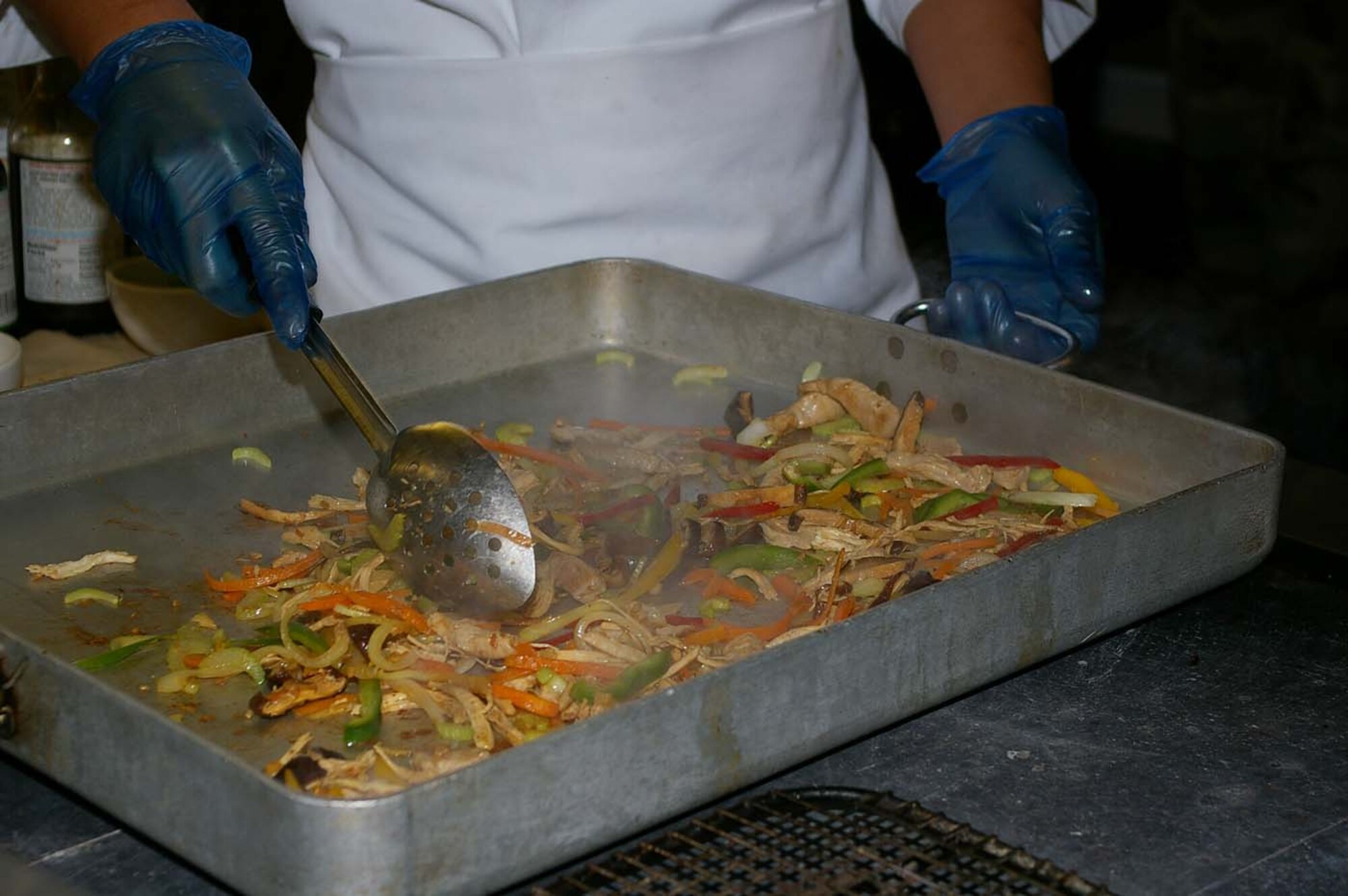 Airman 1st Class Ron Gamo, 100th Services Squadron, cooks pancit at the Gateway Dining Facility May 4 as part of a cooking demonstration for Asian-Pacific Heritage Month. He also showed audience members how to cook chicken adobo and shrimp fried rice. (U.S. Air Force photo by Karen Abeyasekere)