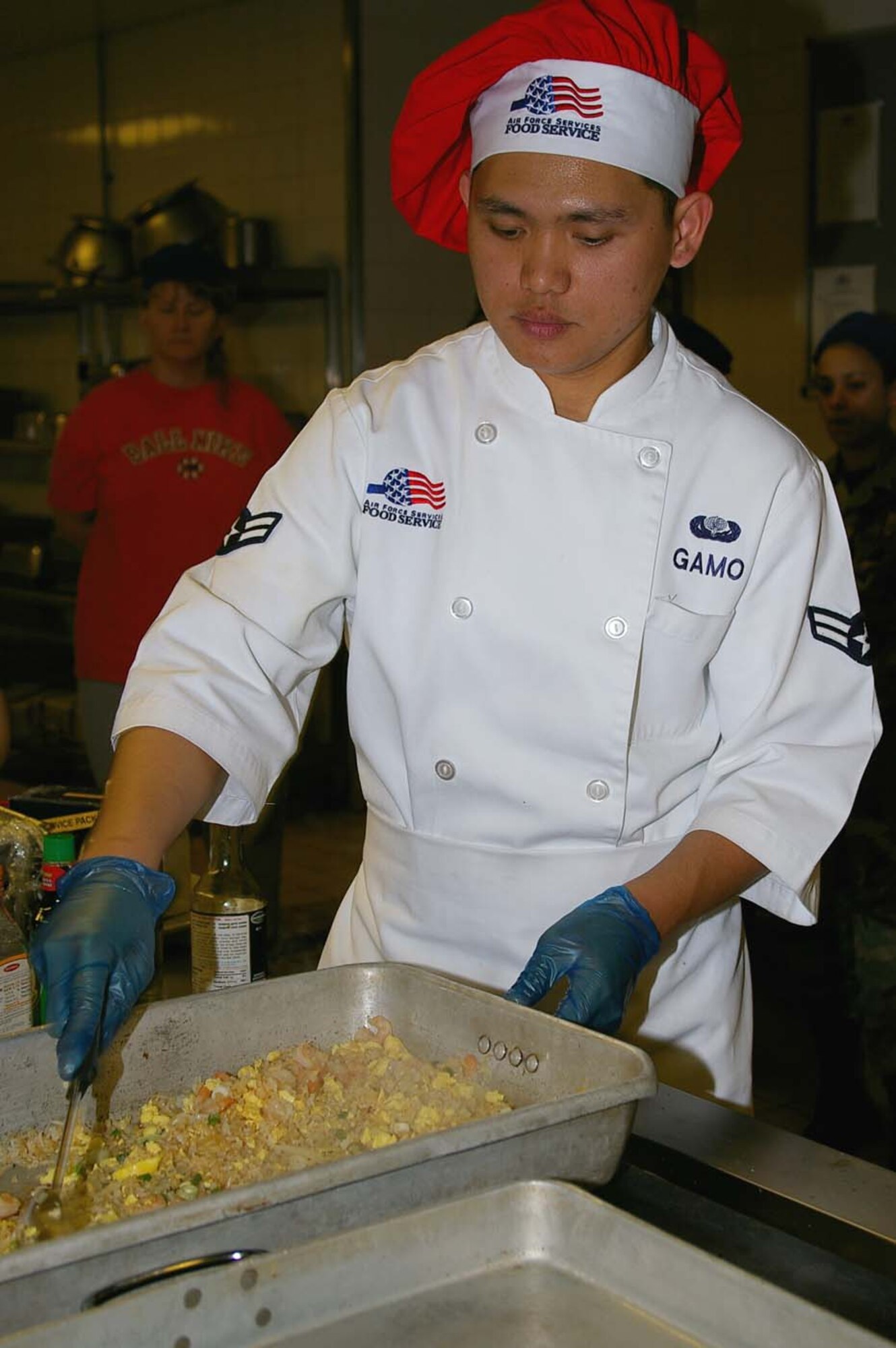 Airman 1st Class Ron Gamo, 100th Services Squadron, shows how to prepare shrimp fried rice at a cooking demonstration in the Gateway Dining Facility May 4 in celebration of Asian-Pacific Heritage Month. Airman Gamo also showed audience members how to cook chicken adobo; they were then able to sample the finished dishes after the demonstration. (U.S. Air Force photo by Karen Abeyasekere)