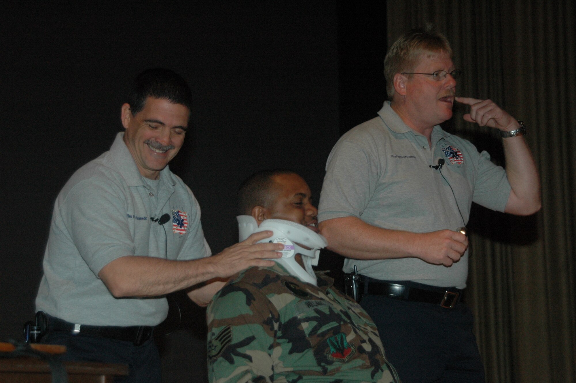 Florida firefighters Ronny Garcia (pictured left) and Kevin Reed demonstrate medical techniques on Staff Sgt. Talmage Williams, 28th Munitions Squadron munitions storage crew chief, during a SAFE brief April 27 at the base theater.  SAFE features members of the medical and law enforcement  community who share their no-hold barred and grittily honest experiences with audiences around the world. (U.S. Air Force photo/Tech. Sgt. Todd Wivell)