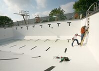 Mavin Brown works to reanchor a ladder at the Warhawk Pool while Jose Herrera stabilizes the work ladder. The two men from the 37th Civil Engineer Squadron on Lackland Air Force Base, Texas, are helping make minor repairs to the pool to ensure its timely opening May 28. Pool hours will be 2-7 p.m. Monday, Wednesday, Thursday and Friday, 1-8 p.m. Saturday and Sunday, closed Tuesday. (USAF photo by Robbin Cresswell)