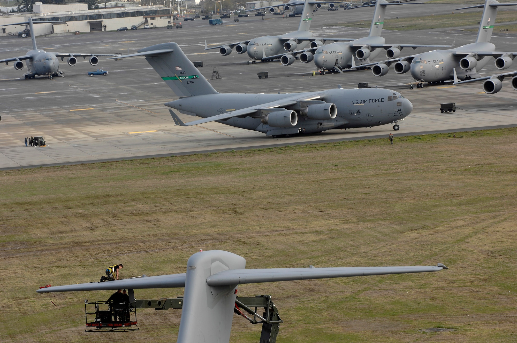 A departing C-17 Globemaster III at McChord Air Force Base, Wash., doesn't distract Airmen replacing an integrated flight control module March 28 on the tail of a C-17.  The Airmen are assigned to the 62nd Aircraft Maintenance Squadron here. Base members are using Air Force Smart Operations for the 21st century to shorten the time of engine running crew change, wing members hope to use three aircraft instead of four for training missions. (U.S. Air Force photo/Abner Guzman)