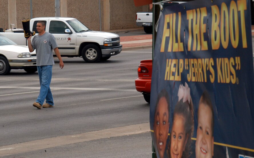 Airman 1st Class William Jenkins, 7th Civil Engineer Squadron firefighter, collects money in a boot at the intersection of Southwest Dr. and the Winters Freeway May 11. The Abilene and Dyess fire departments partnered together for a Muscular Dystrophy fund-raiser, and thanks to the local community raise $41,733 in three days. (U.S. Air Force photo by Airman 1st Class Carolyn Viss)                                