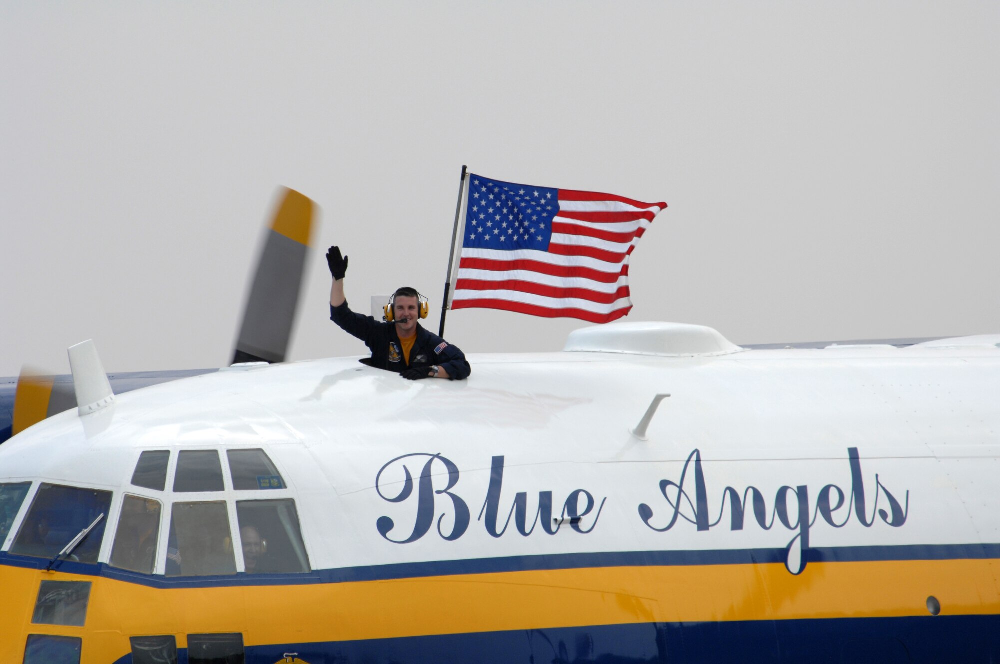 A member of the Blue Angels "Fat Albert" team carries an american flag and waves to the crowd at the Wings Over Wayne Airshow here May 12. The Wings Over Wayne Airshow 2007 is the first apperance of the Blue Angels since the accident that occurred April 21.(U.S. Air Force photo by Airman 1st Class Greg Biondo)(released)