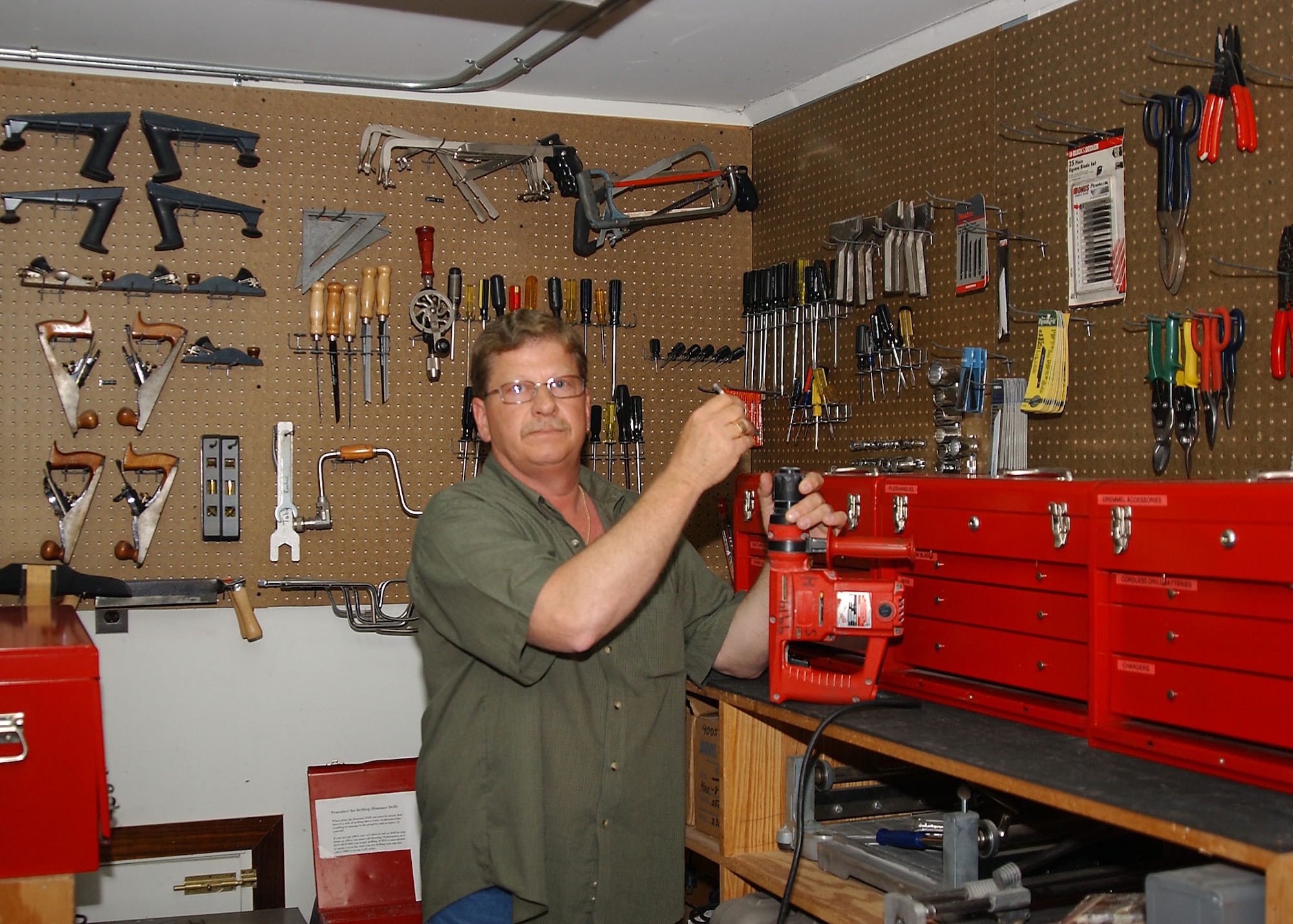 Perry Atchley, a self-help employee, shows the proper technique to putting in a drill bit at the Self-Help store tool crib May 7.  (U.S. Air Force photo by Tech. Sgt. Patrick Hyde)