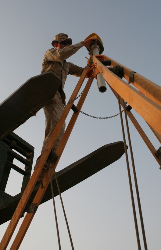 AR RAMADI, Iraq- Sgt. Randy Edwards, a Marine Wing Support Squadron 371 heavy equipment operator, installs the spectrum precision laser level on its base, May 17.  The laser level is mounted on a tripod and sends a signal to the receiver mounted on the 130 G grader and controls the blade.